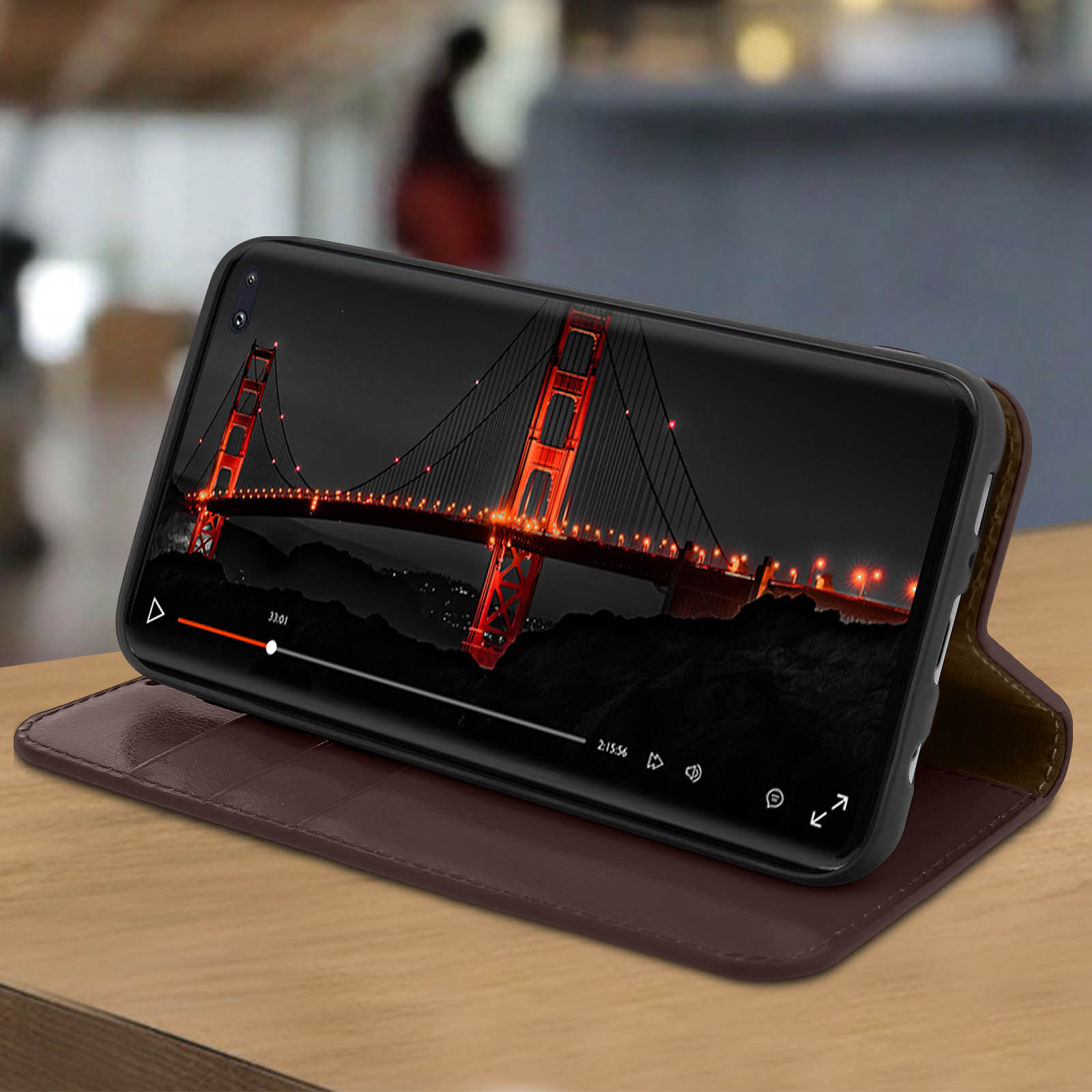 Smartphone che mostra una vista del ponte. Telefono in una custodia marrone, su un tavolo di legno. Sfondo sfocato.