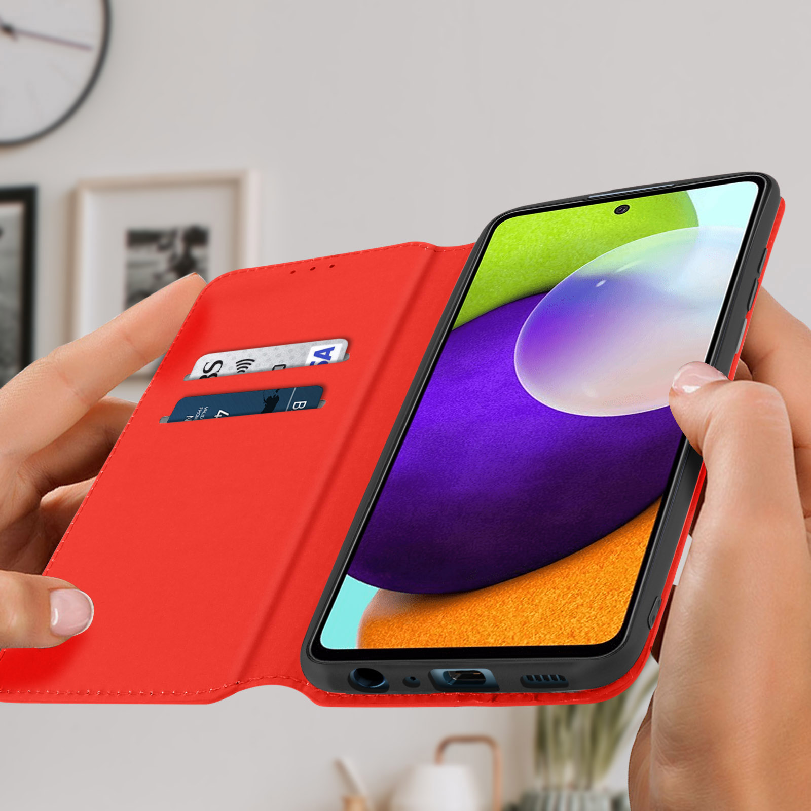 Una custodia rossa per telefono con un telefono e carte di credito. Il telefono ha lo schermo acceso.