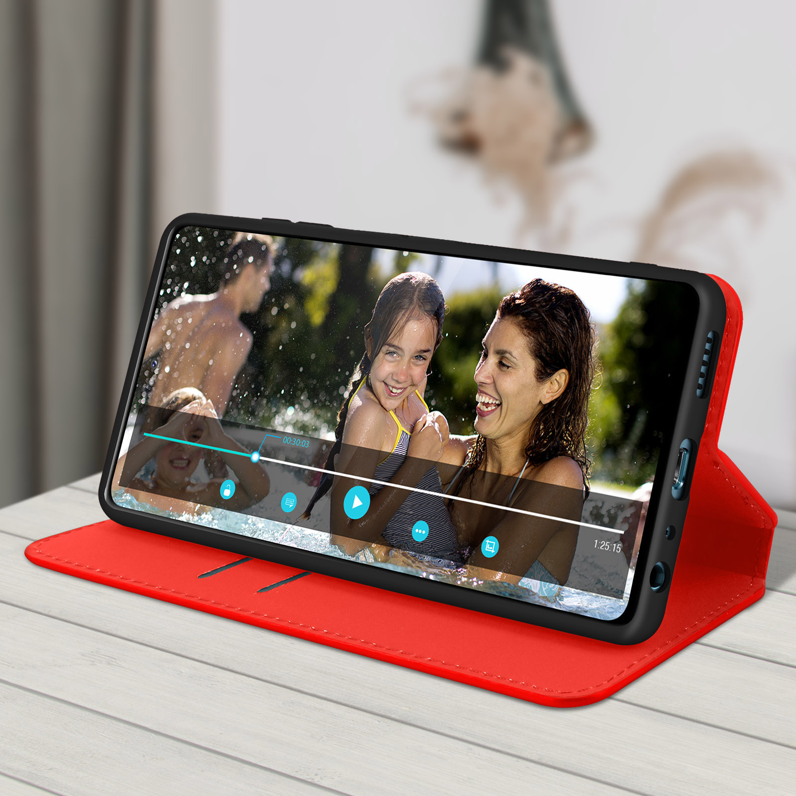Telefono in custodia rossa, mostra video di famiglia in piscina. Donna sorride.