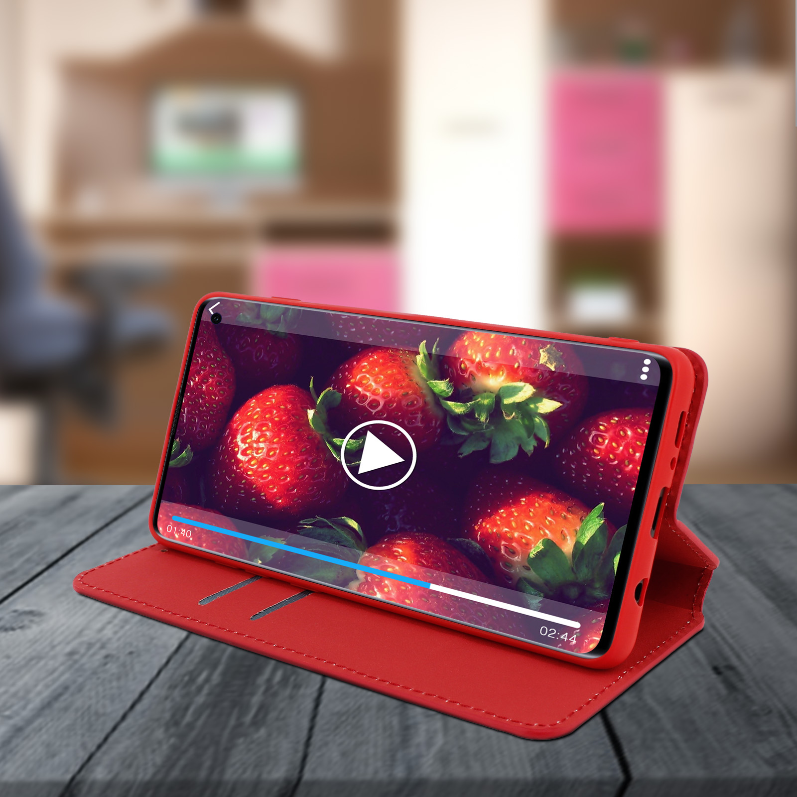 Custodia per telefono rossa con telefono che mostra un video di fragole. Pulsante di riproduzione visibile sullo schermo.