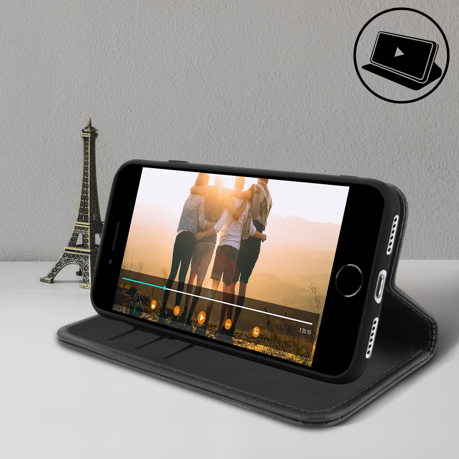 Un telefono che mostra un video con persone su un supporto. C'è una Torre Eiffel in miniatura a sinistra.