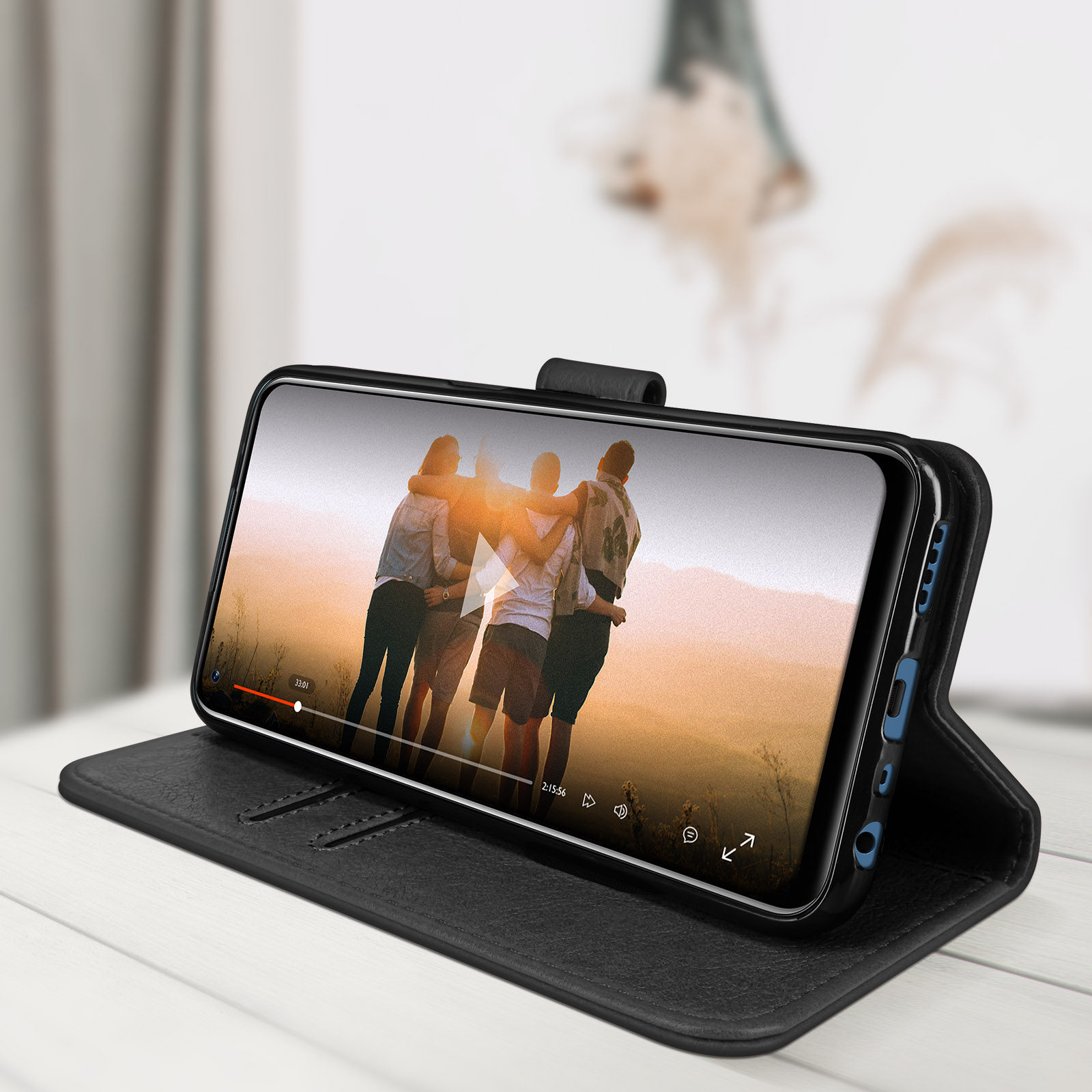 Téléphone noir dans un étui affiche une vidéo d'amis. L'étui est sur une table.