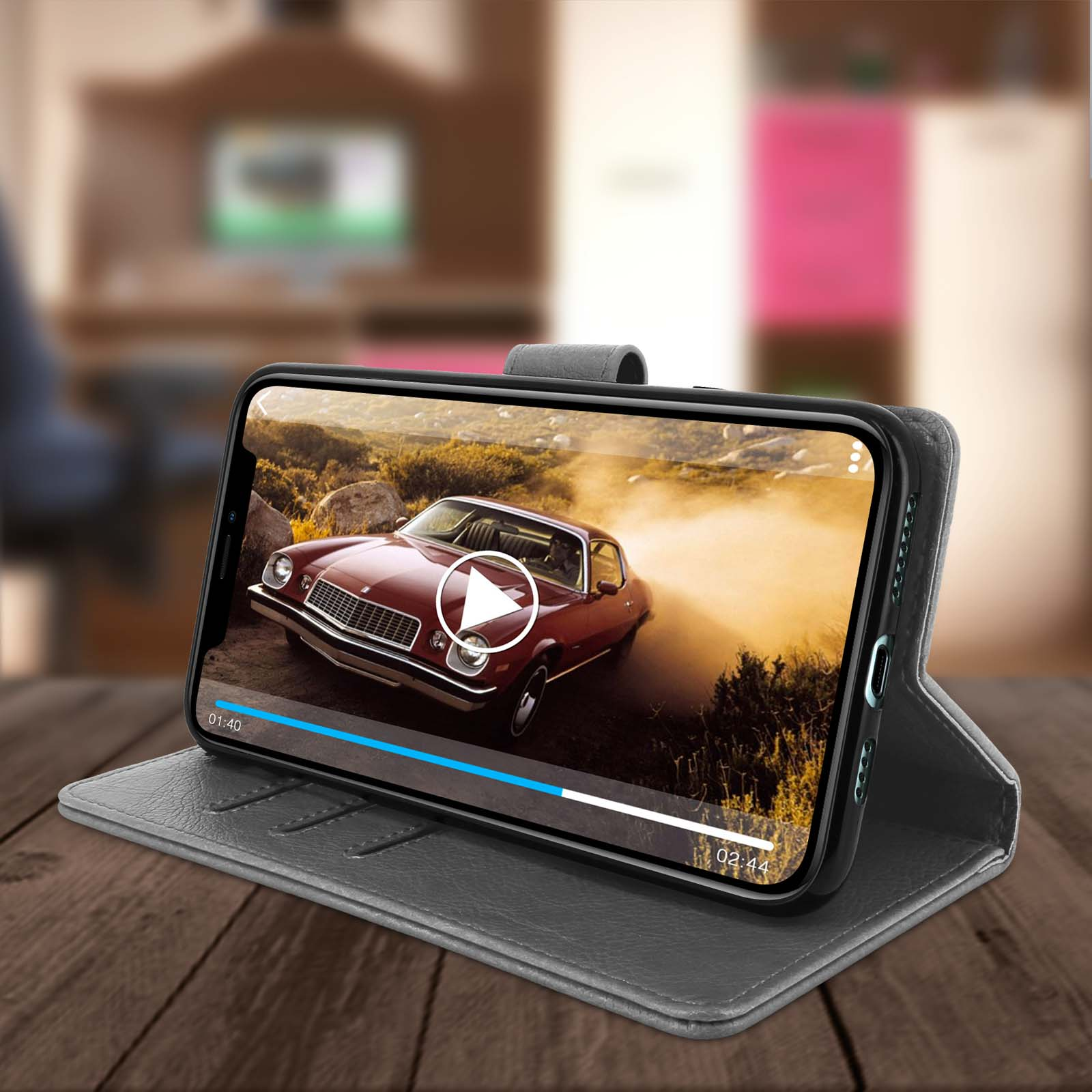 Een telefoon met een autovideo in een hoesje op een houten tafel.