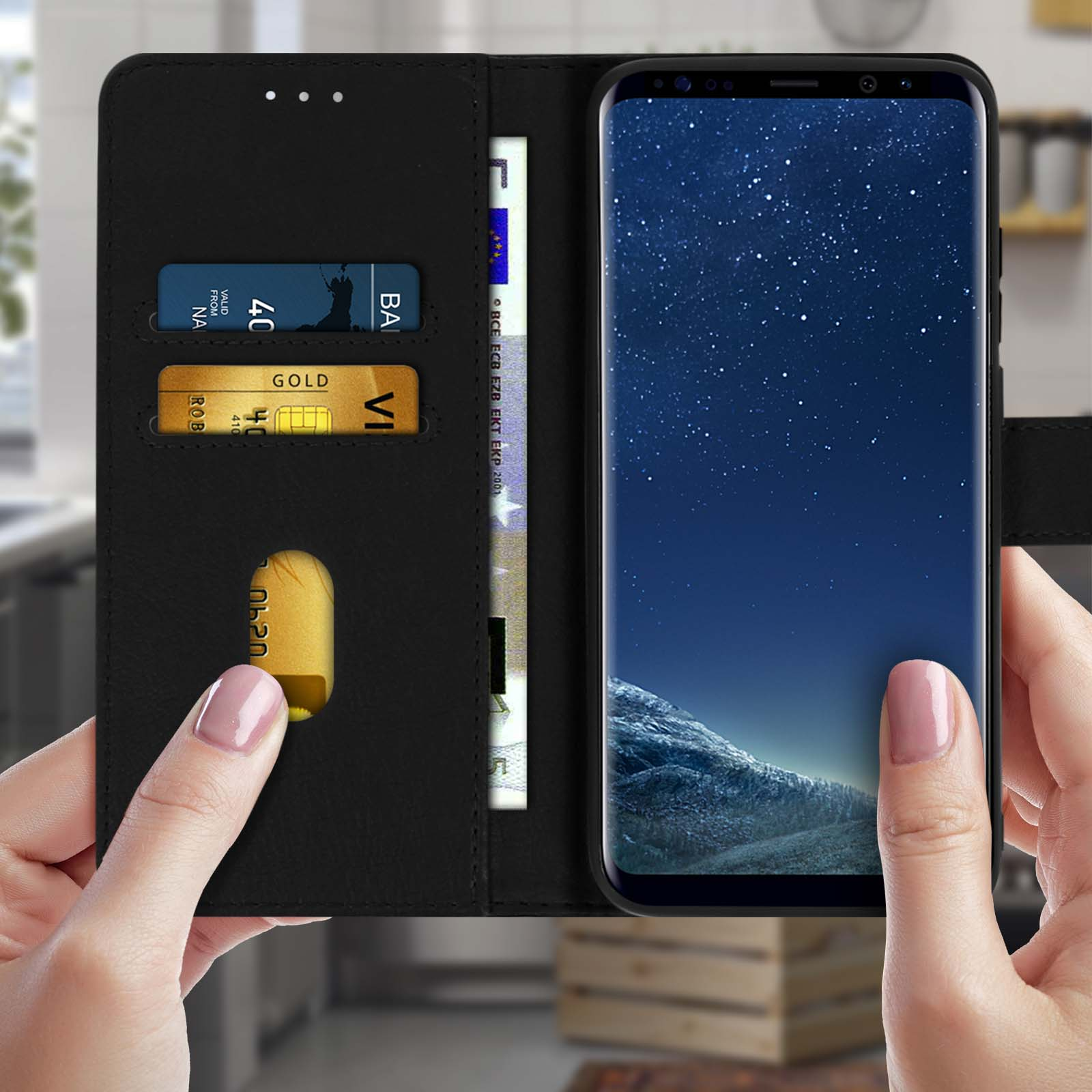 Zwarte telefoonhoes open, met een telefoon met een screensaver van een sterrenhemel. Twee handen houden de telefoon vast.