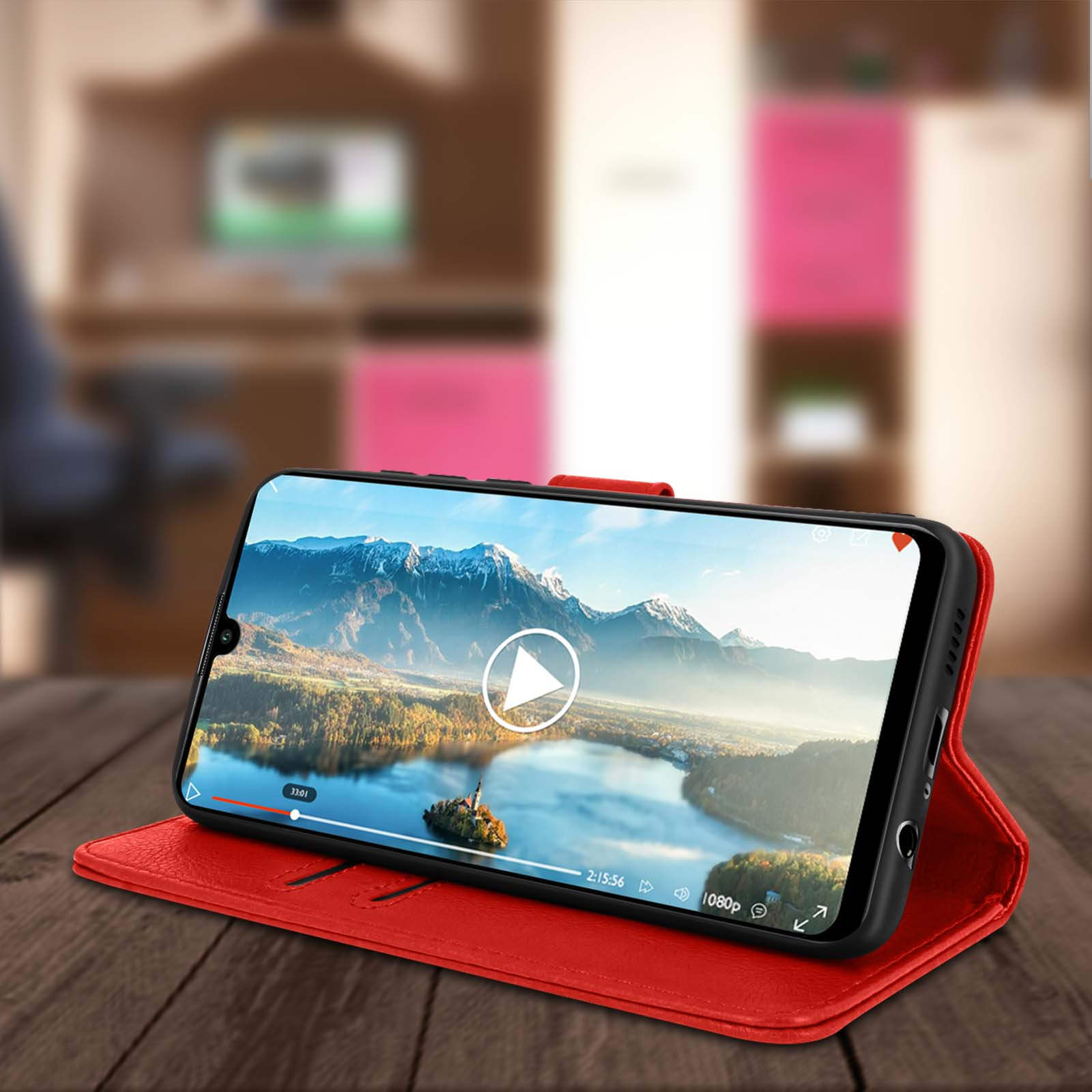 Telefono con video in riproduzione. In custodia rossa, su tavolo in legno. Montagne e acqua visibili sullo schermo.