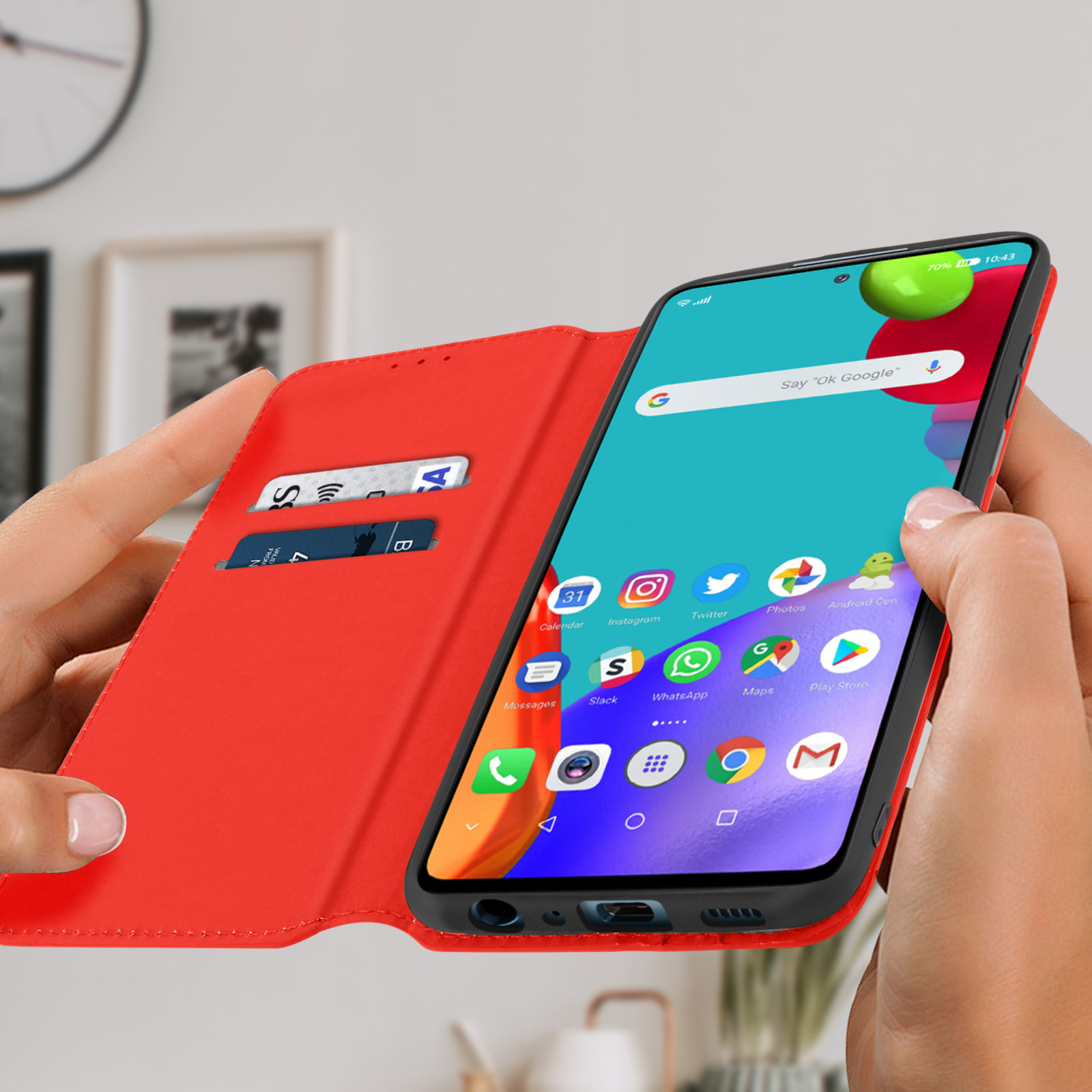 Una persona tiene una custodia rossa per telefono. Lo schermo del telefono mostra l'ora, le notifiche e una schermata iniziale.