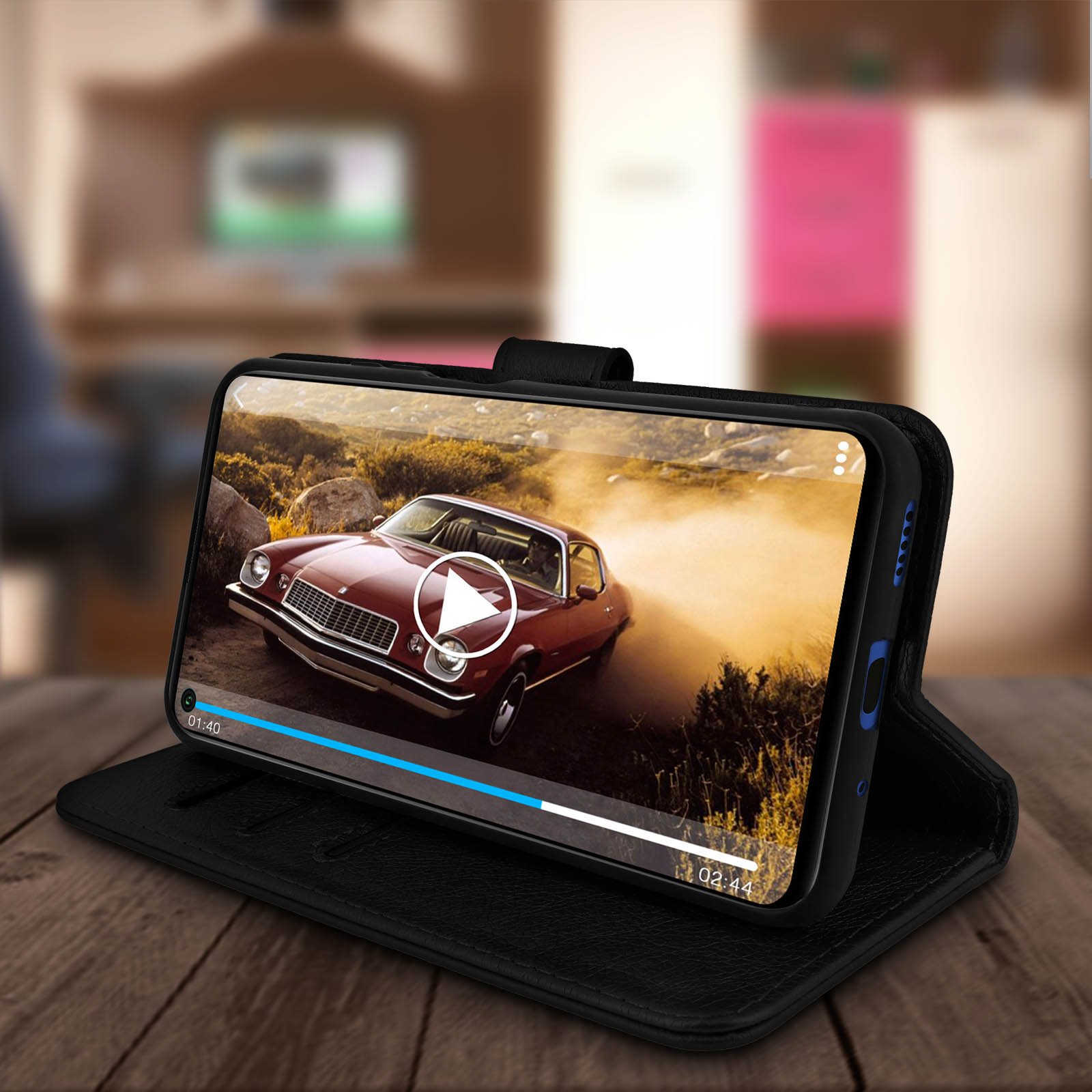 Smartphone en una funda negra reproduciendo un video en una mesa de madera. Fondo borroso.