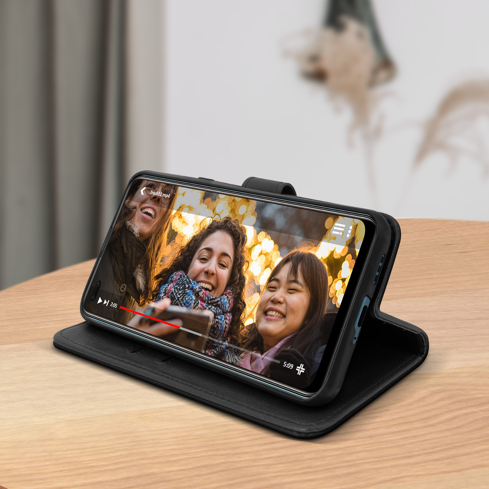 Telefon in schwarzem Gehäuse, spielt Video von drei lächelnden Personen ab.