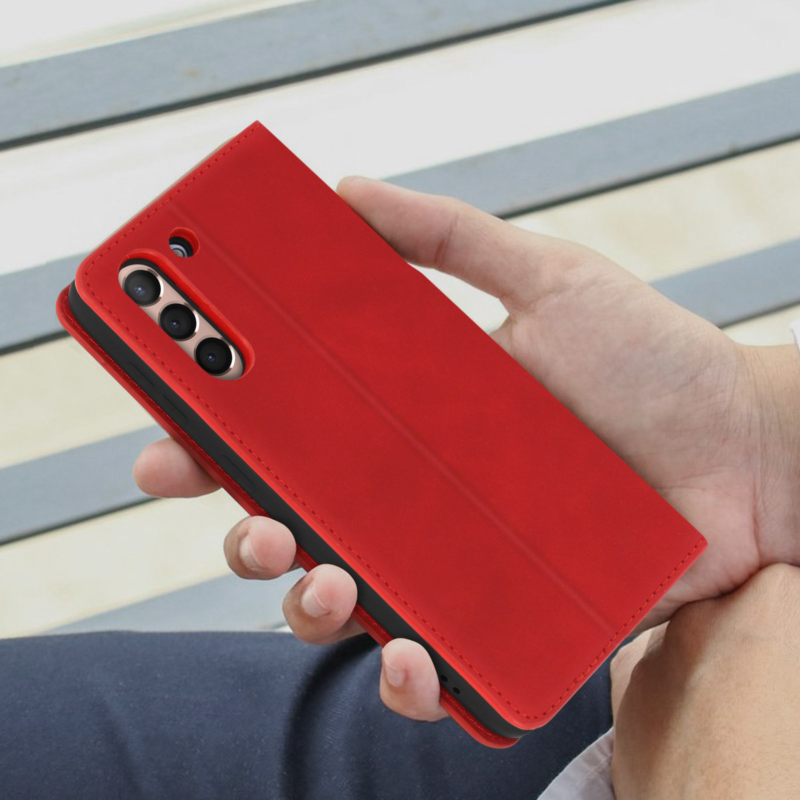 Mano che tiene una custodia rossa per telefono. Il telefono è all'interno della custodia ed è visibile.