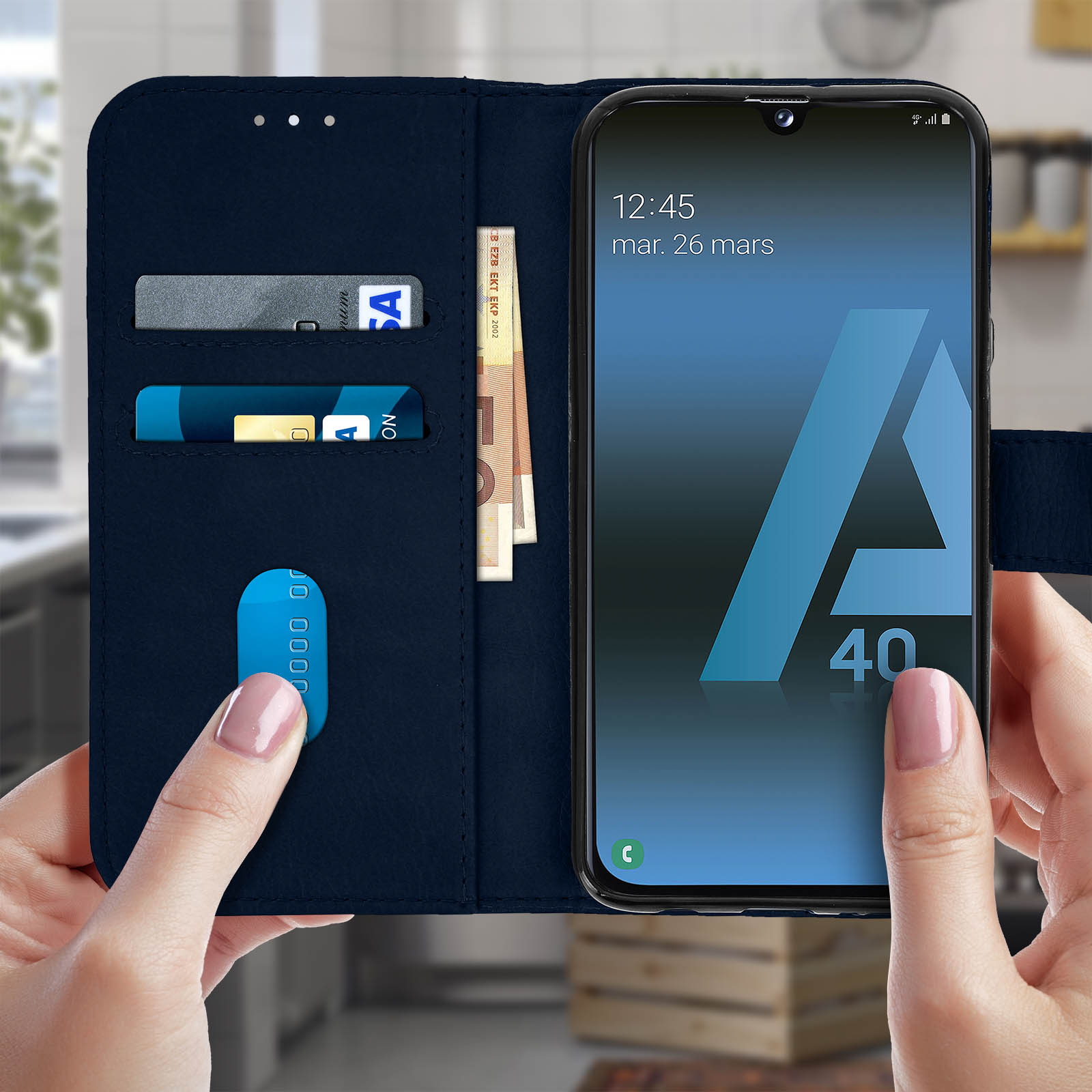 Marineblauwe telefoonhoes met kaarten, geld en een telefoon in handen.