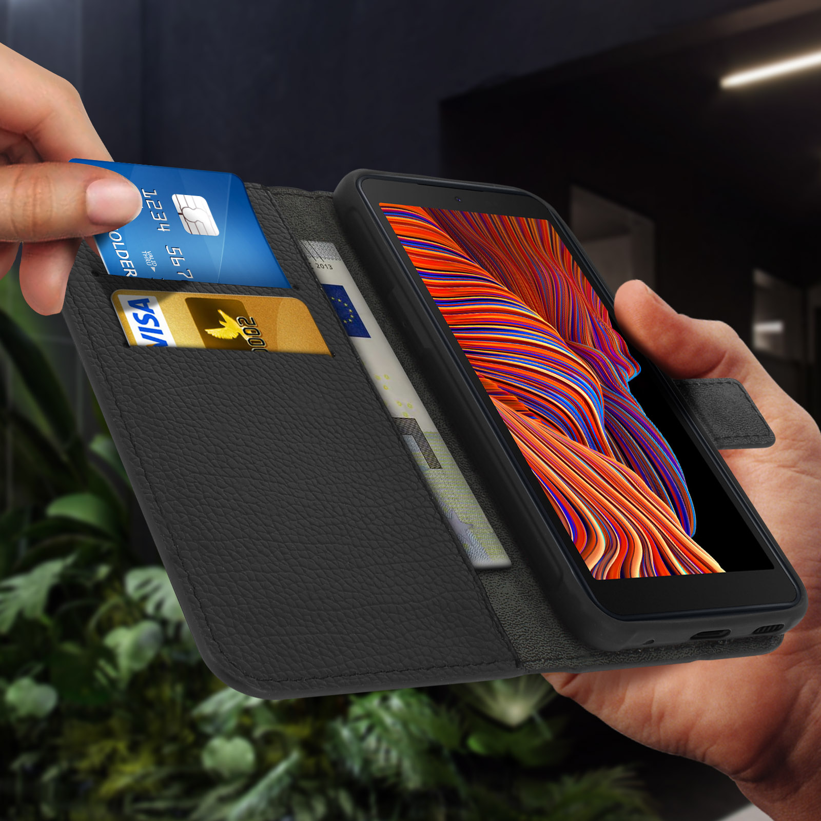 Mains tenant un téléphone noir dans un étui portefeuille. Cartes de crédit et espèces visibles. L'arrière-plan est flou.
