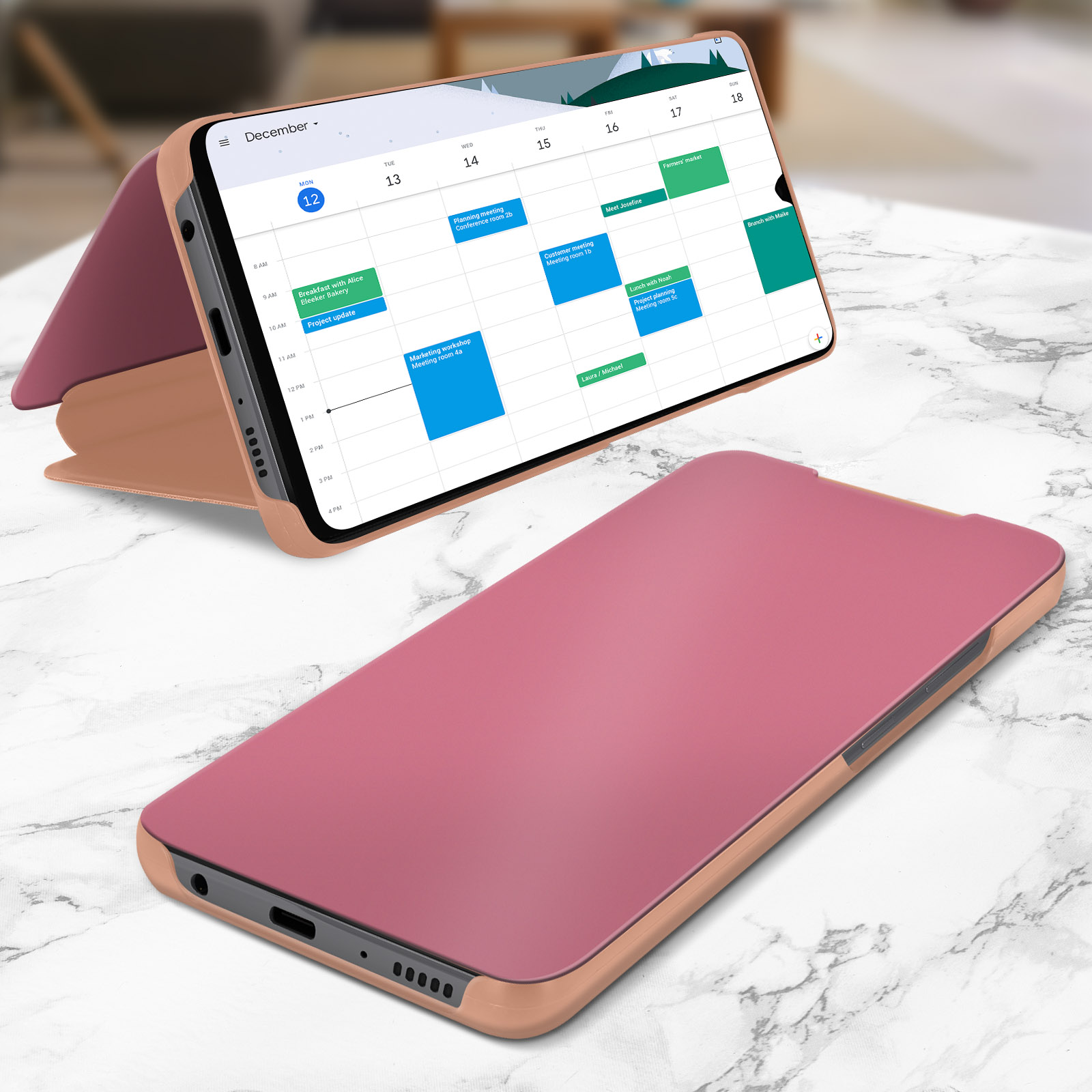 Un teléfono rosa en una funda está abierto mostrando un calendario. La funda está sobre una superficie de mármol blanco.