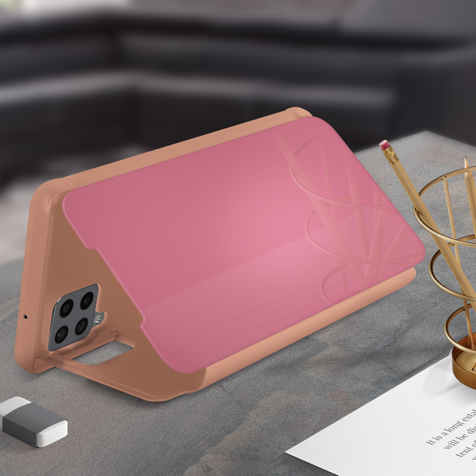 Funda rosa para teléfono en un escritorio. El teléfono está en la funda. Lápiz y otros elementos son visibles.