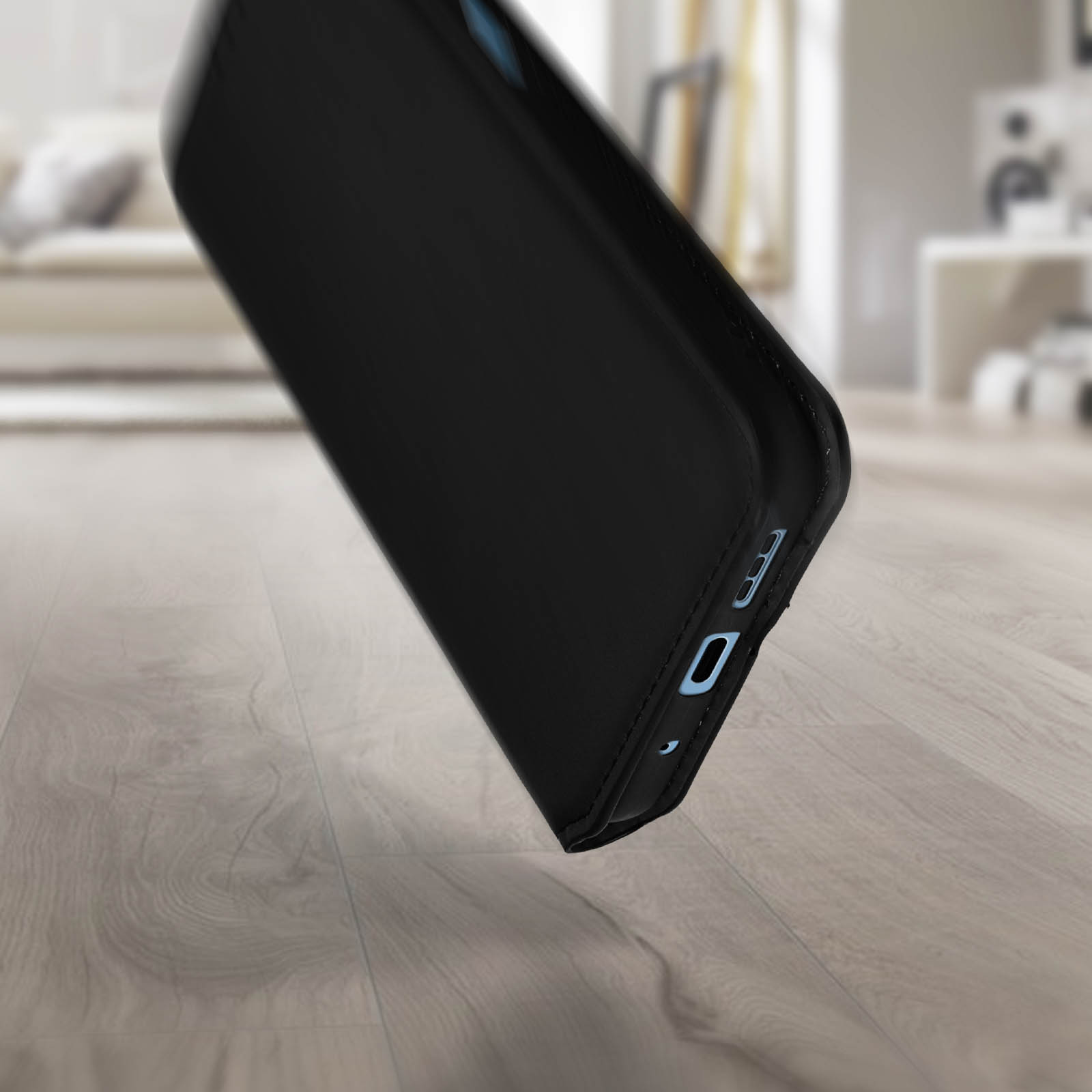 Un étui de téléphone noir tombe sur un sol en bois. Le téléphone est visible.