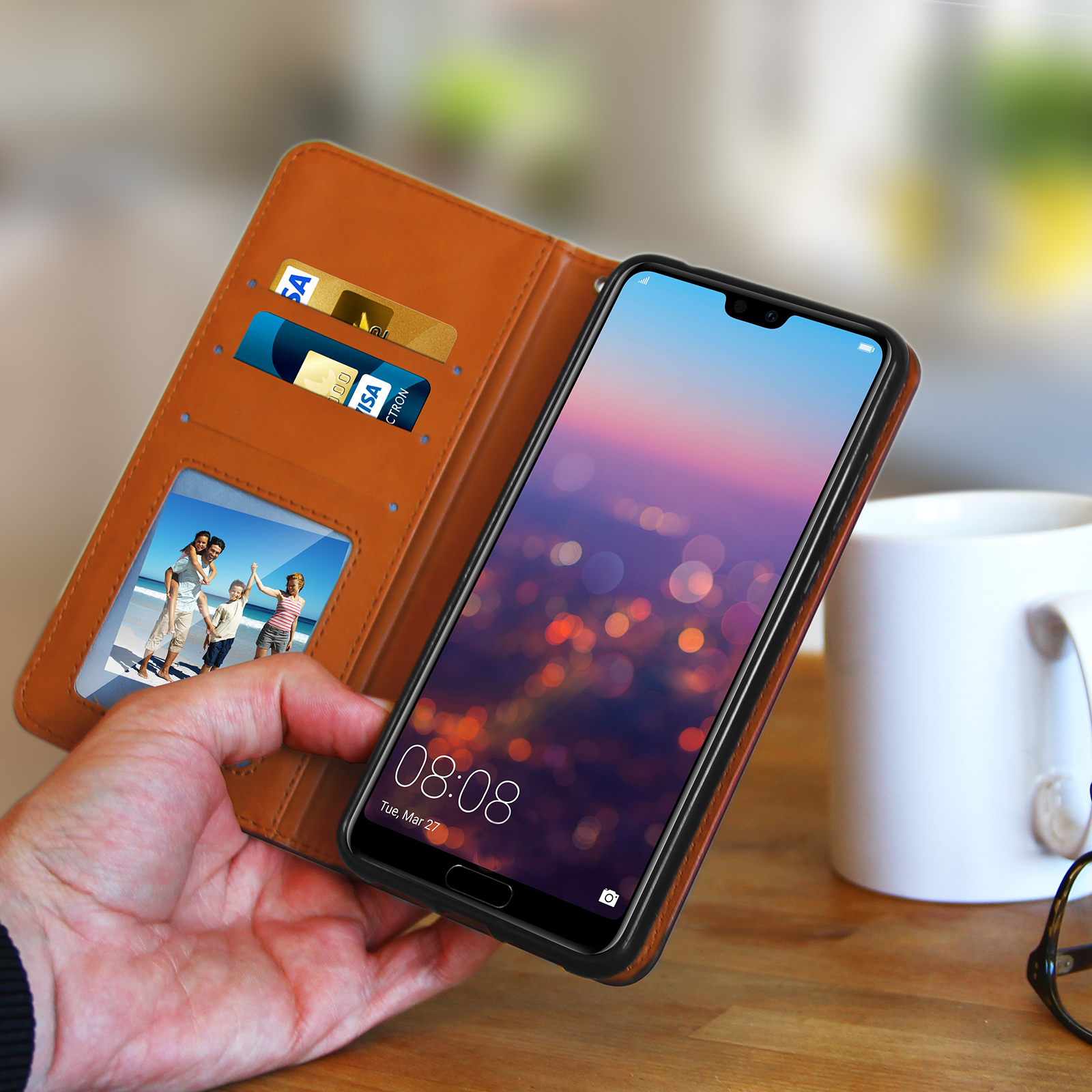 Mano che tiene il telefono in una custodia in pelle aperta. Il telefono mostra una foto di famiglia e carte di credito.