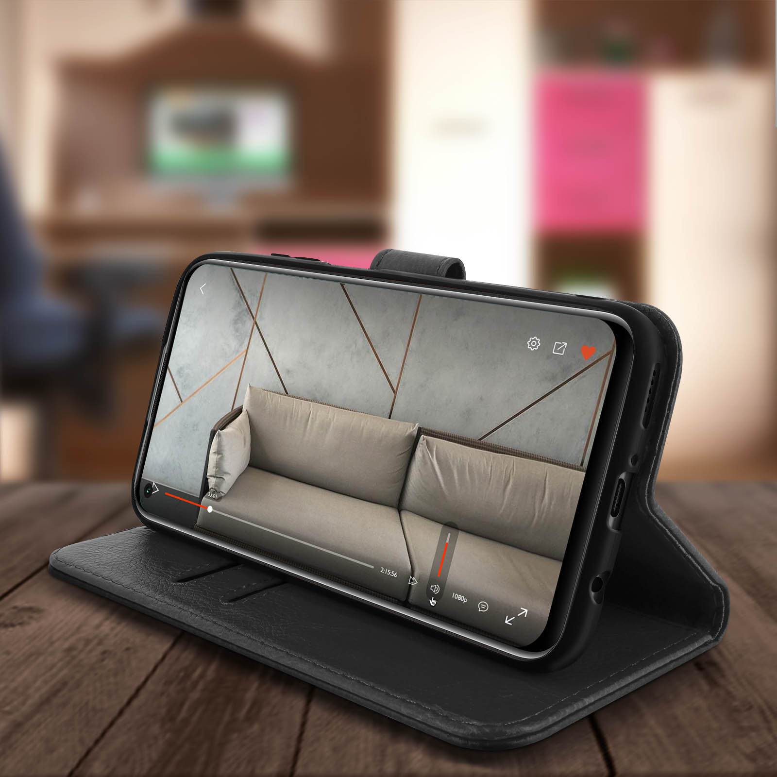Zwarte telefoon in een hoesje met een video van een bank op een houten tafel in een kamer.