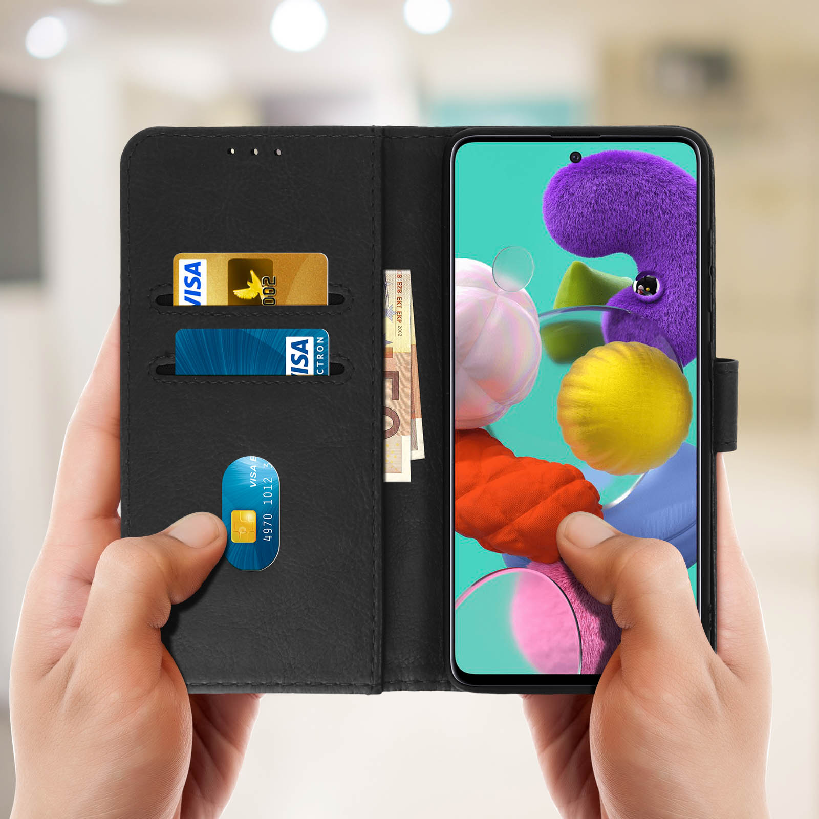 Mains tenant un étui de téléphone noir avec cartes, argent et écran de téléphone.