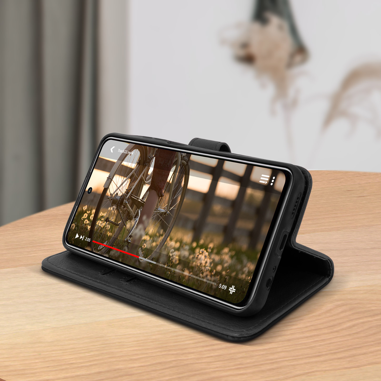 Eine schwarze Handyhülle mit einem Telefon darin, das ein Video auf einer Holzoberfläche zeigt.