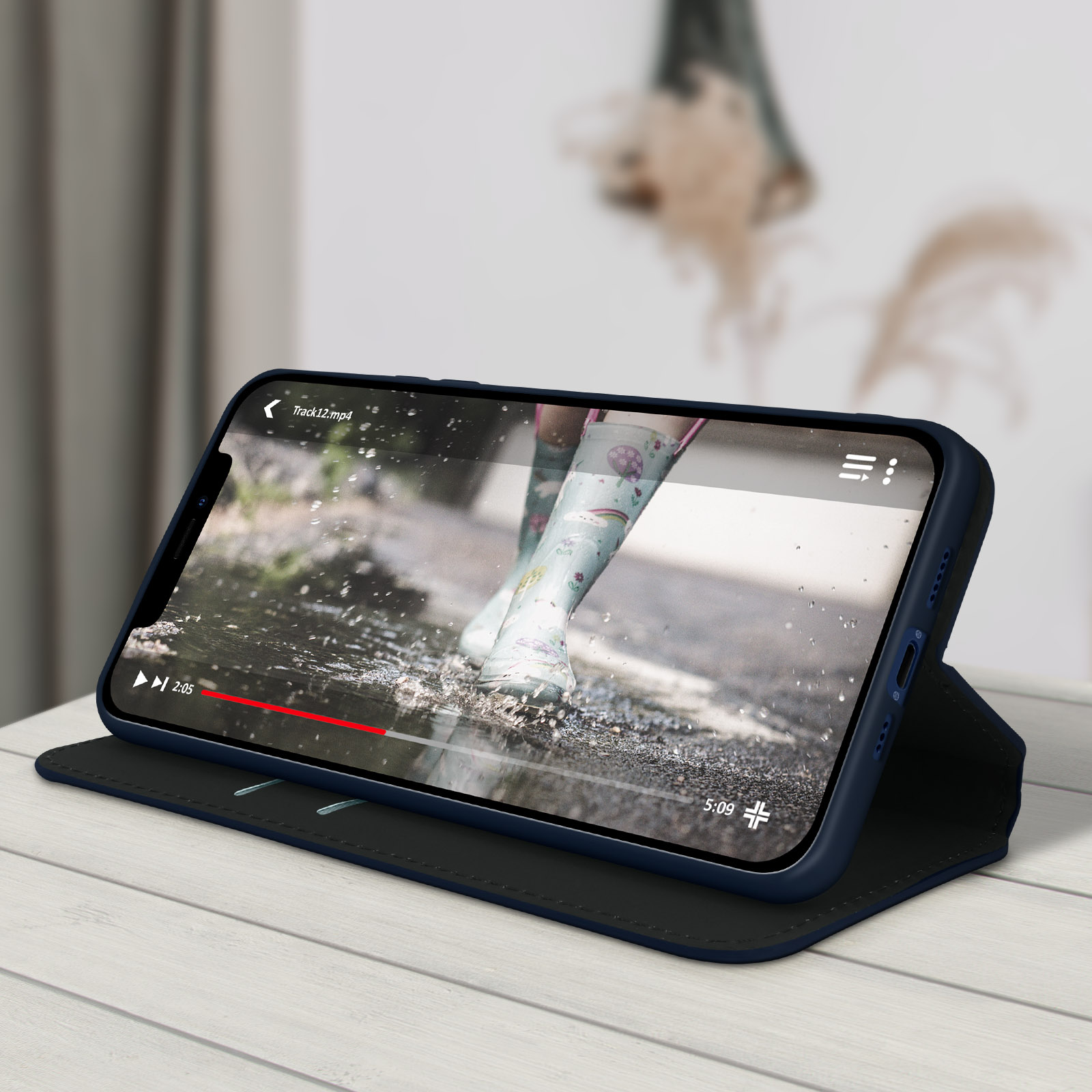 Telefono con video che mostra una persona con stivali da pioggia. Il telefono è su un tavolo di legno.