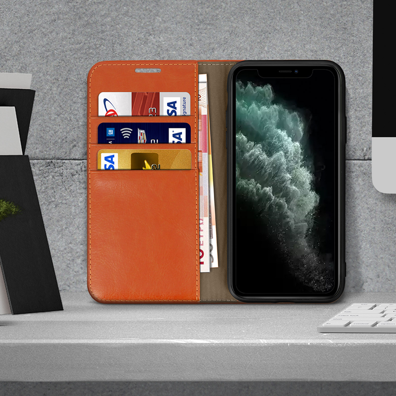 Een telefoon in een oranje portemonneehoes. Kaarten en geld zijn zichtbaar, op een oppervlak.