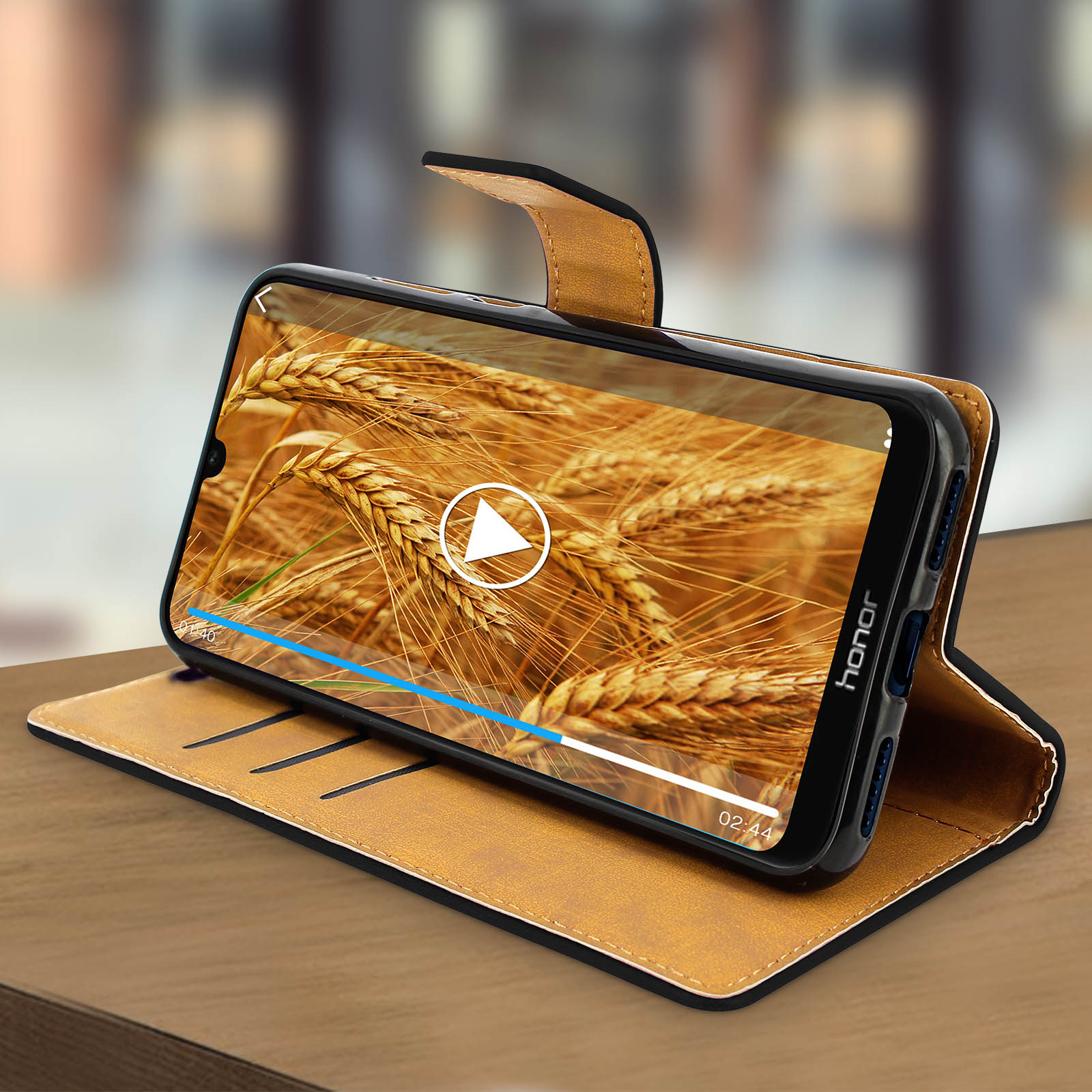 Telefono in una custodia che riproduce un video di un campo di grano con un pulsante di riproduzione. La custodia è aperta.