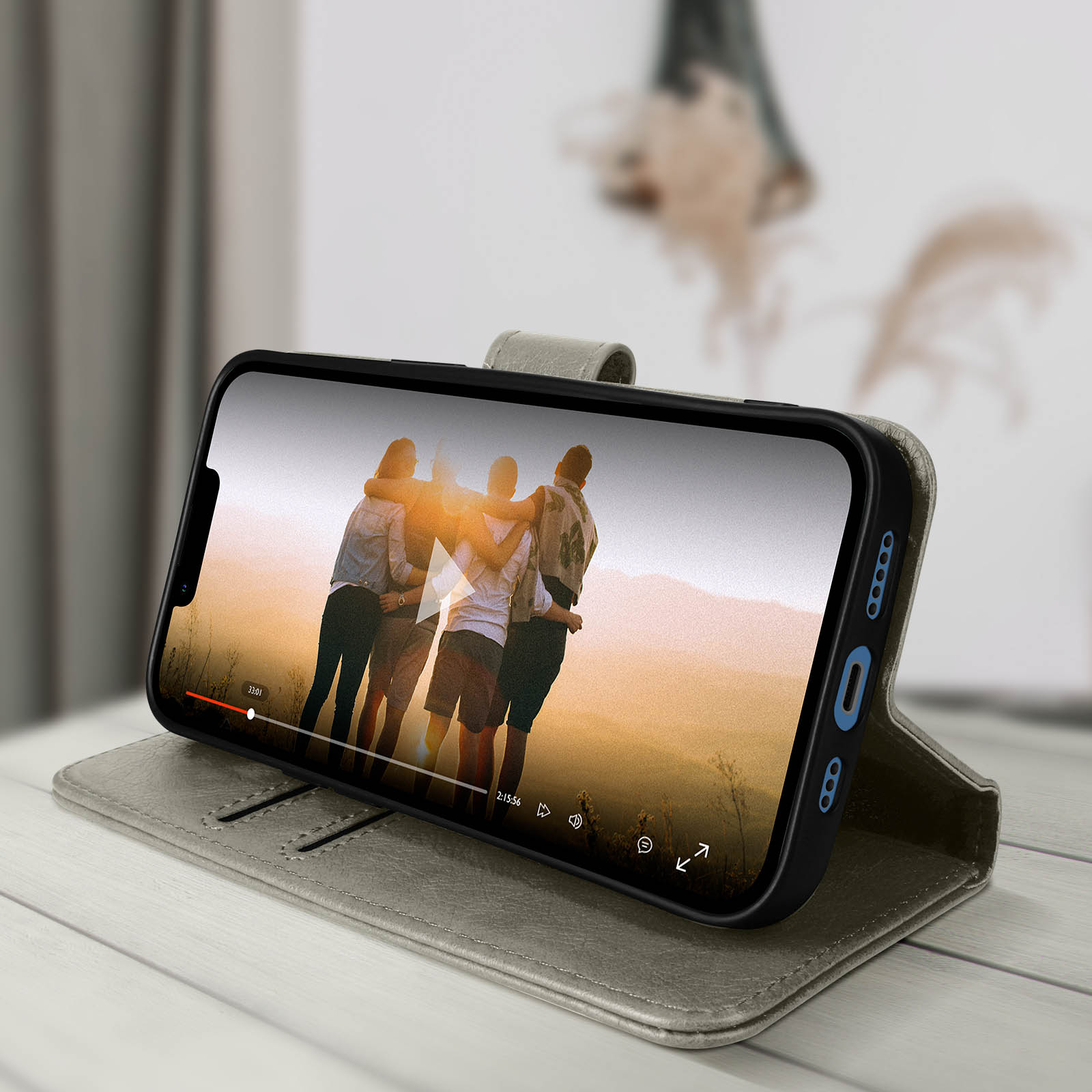 Telefono in una custodia che mostra un video di persone che si abbracciano. Tavolo di legno.