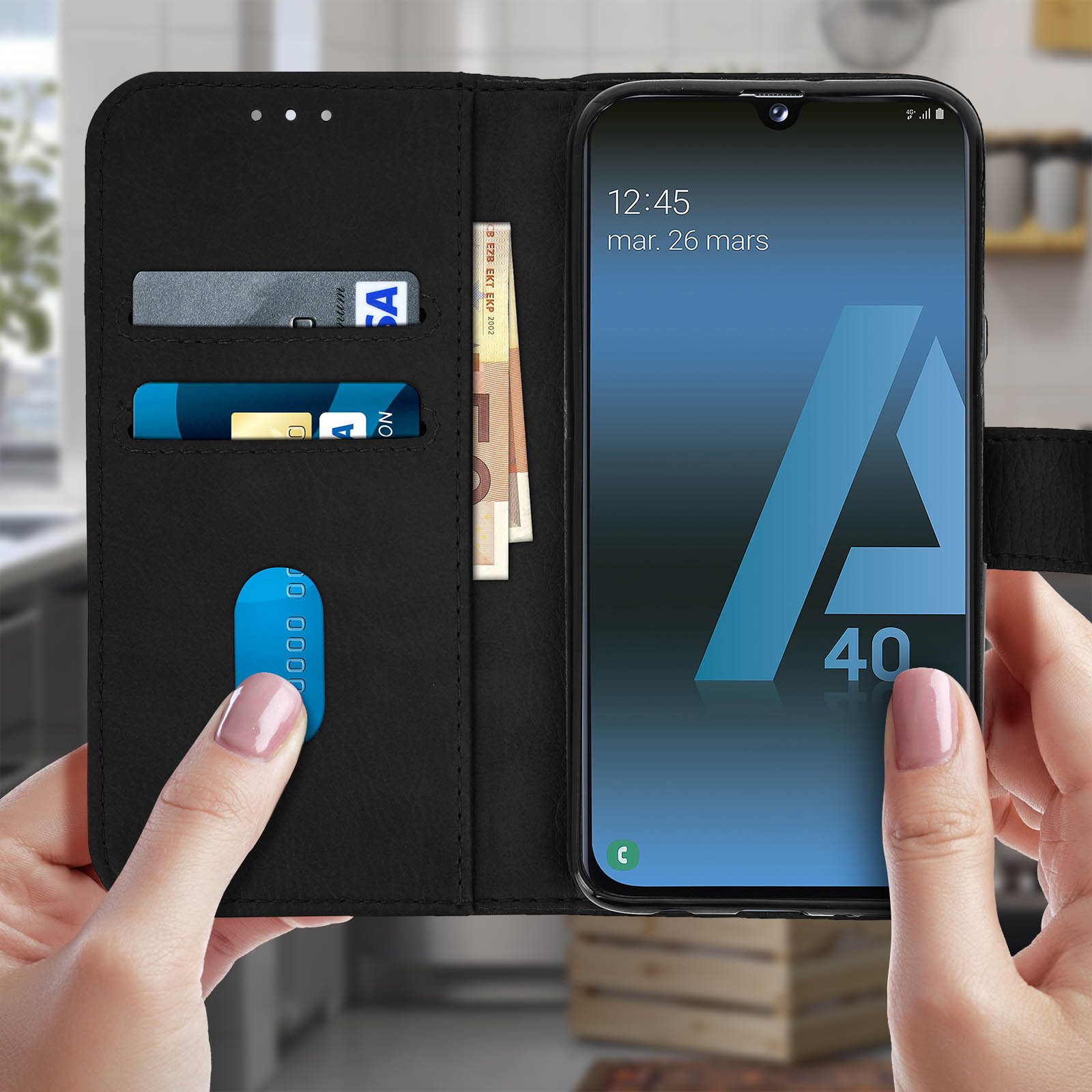 Telefoon met bankpassen en eurobiljetten in een zwart leren hoesje. Een hand houdt het vast.