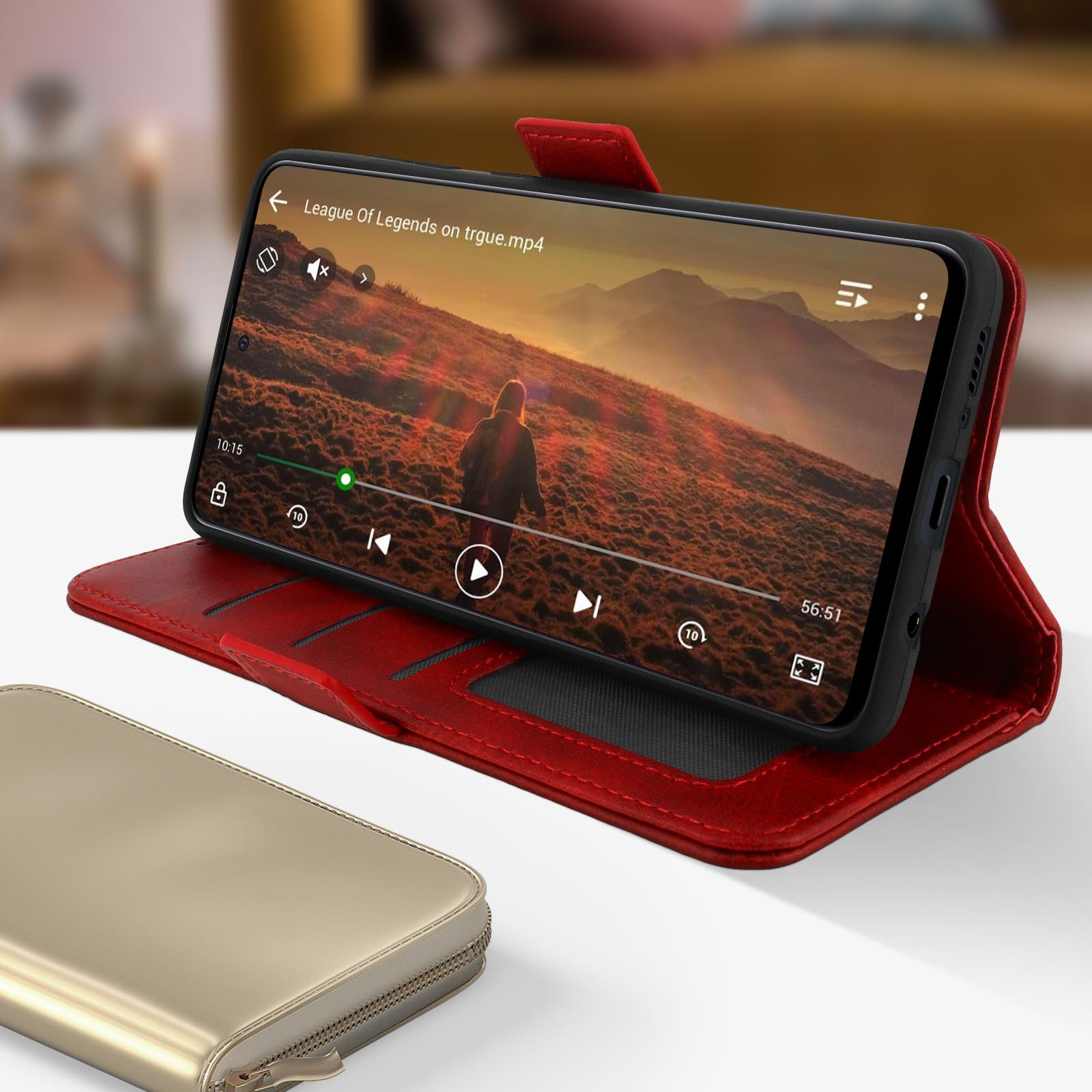 Telefono in custodia rossa che riproduce un video. Portafoglio dorato in primo piano.