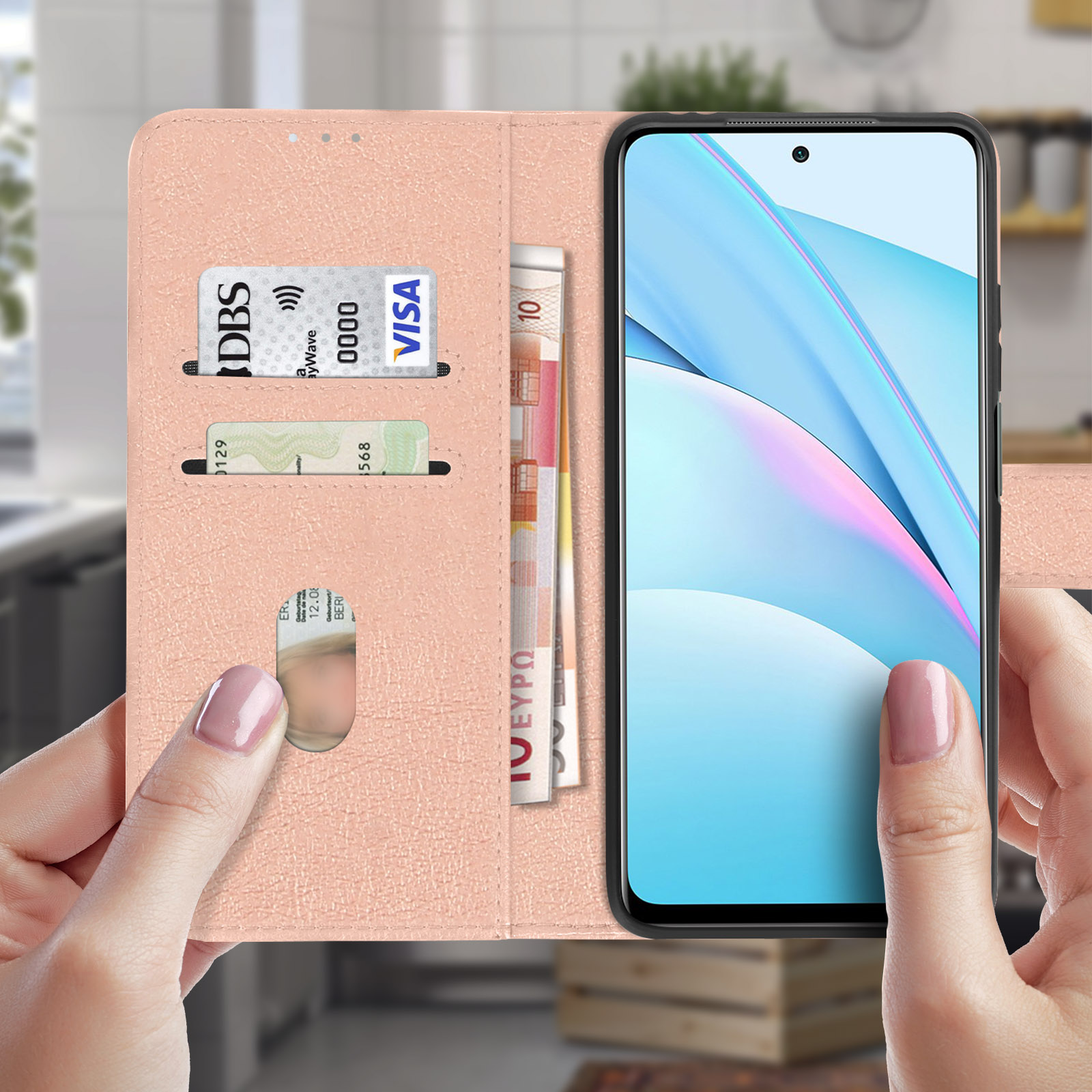 Un telefono in una custodia rosa con una carta e denaro. La mano di una donna tiene aperta la custodia.