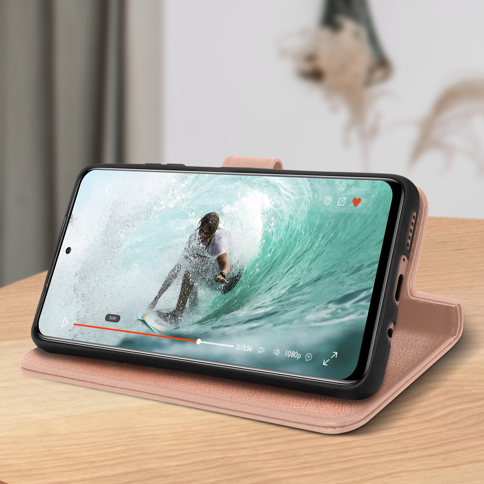 Smartphone in una custodia rosa che riproduce un video di un surfista su un'onda.