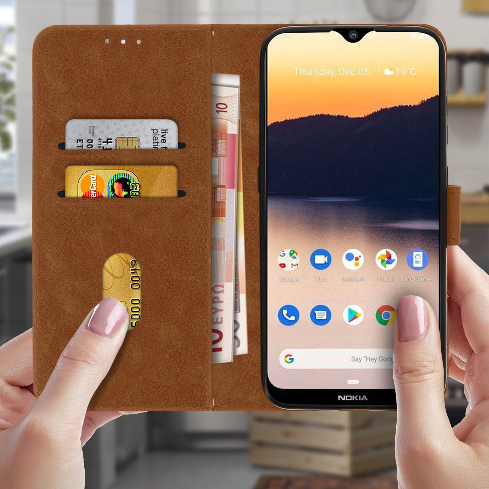 Un téléphone dans un étui de style portefeuille marron ouvert. Cartes de crédit et argent dans les fentes. Main le tenant.