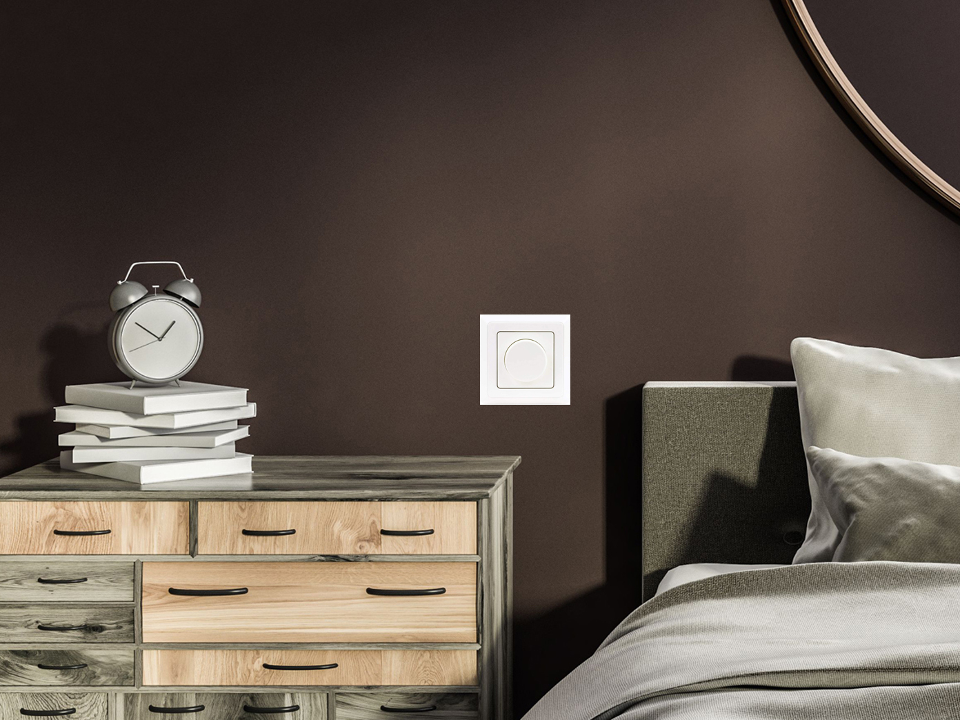 Ein weißer Dimmschalter an einer braunen Wand über einer Holzkommode und einem Bett.