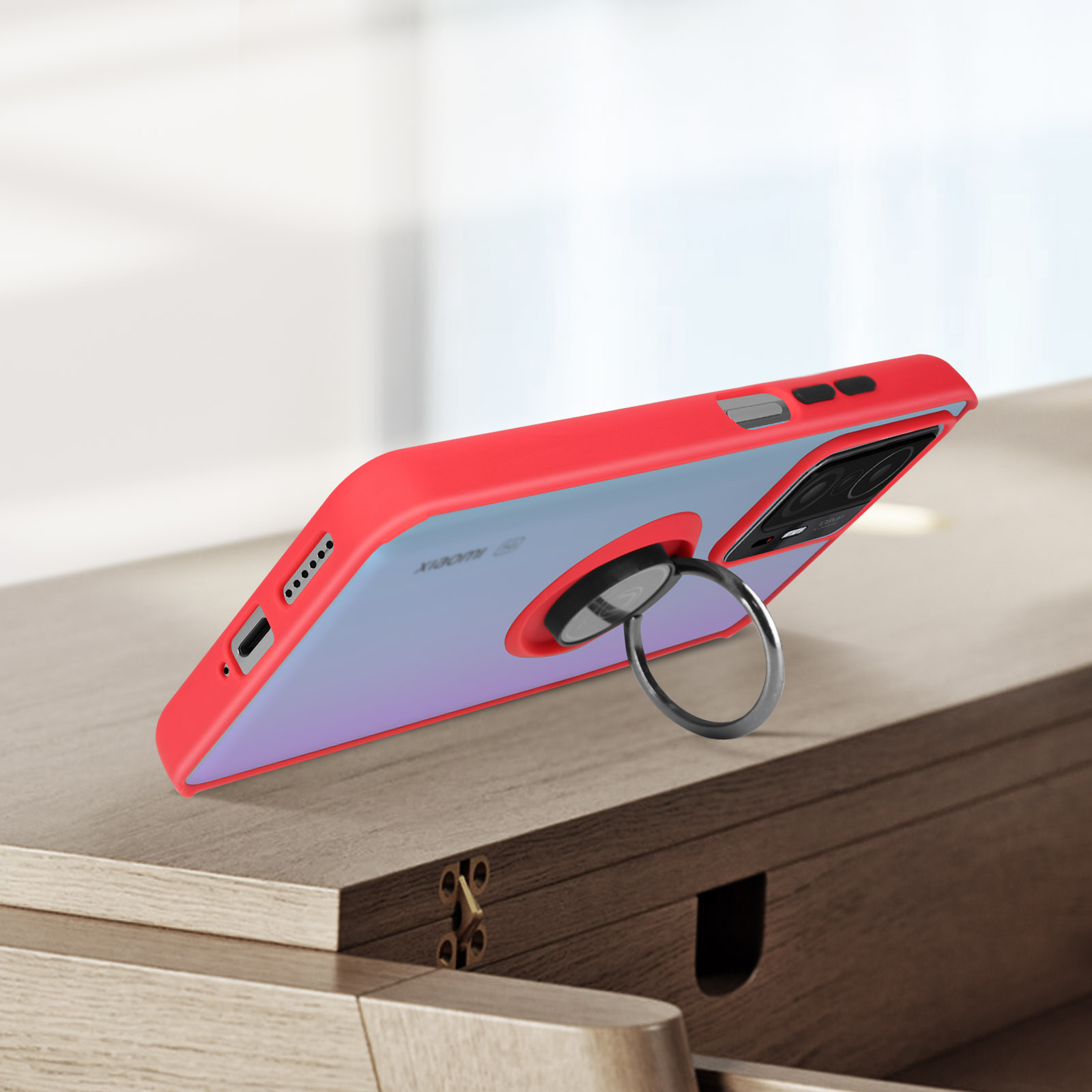 Una custodia per telefono rossa e trasparente con un supporto ad anello. Il telefono è su una superficie di legno.