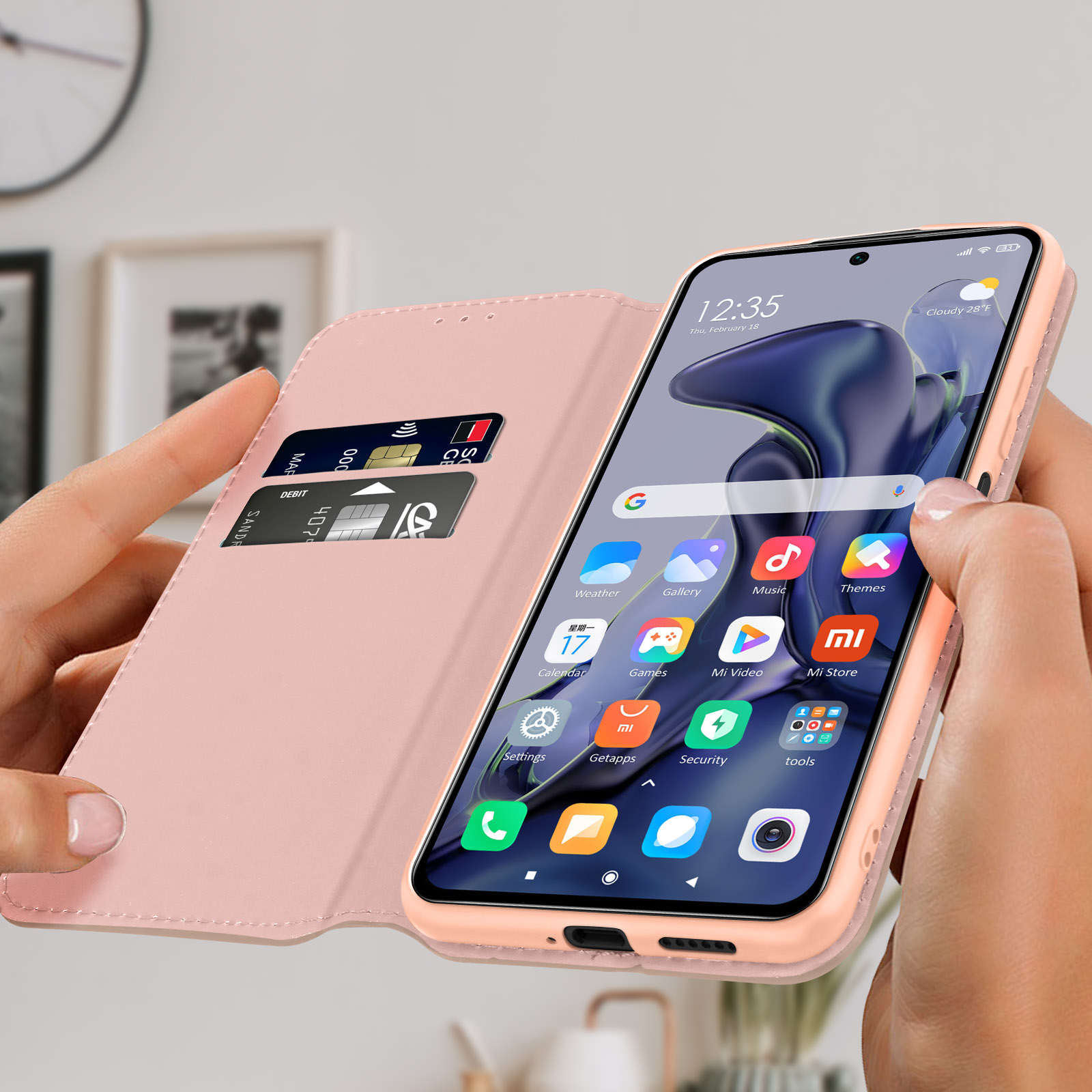 Persona che tiene in mano un telefono con custodia rosa aperta, mostrando schermo con icone e carte.
