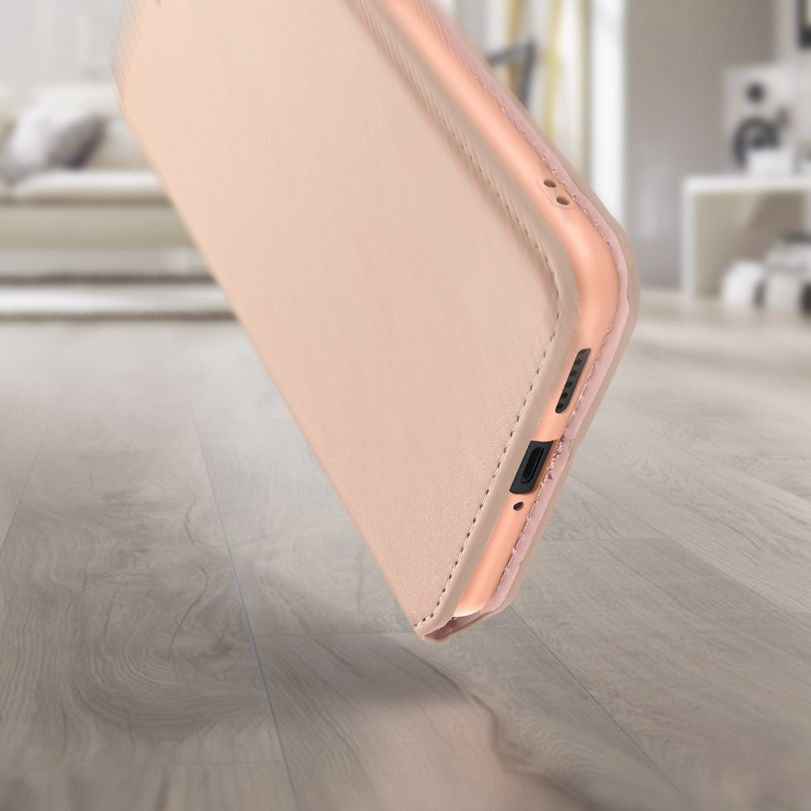Una custodia per telefono oro rosa che cade, mostrando i bordi laterali e superiori, con sfondo sfocato.