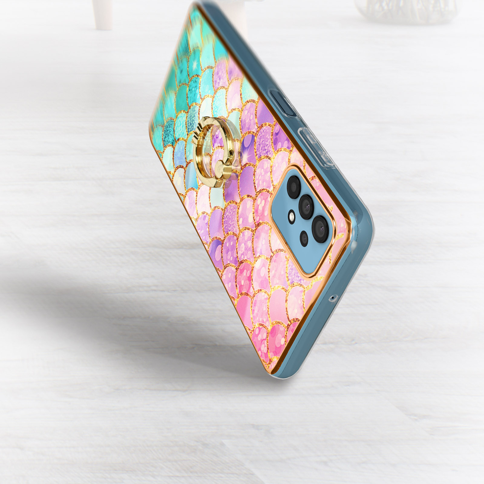Ein Smartphone in einer Hülle mit Meerjungfrauenschuppen-Design. Die Hülle hat einen goldenen Ringhalter.