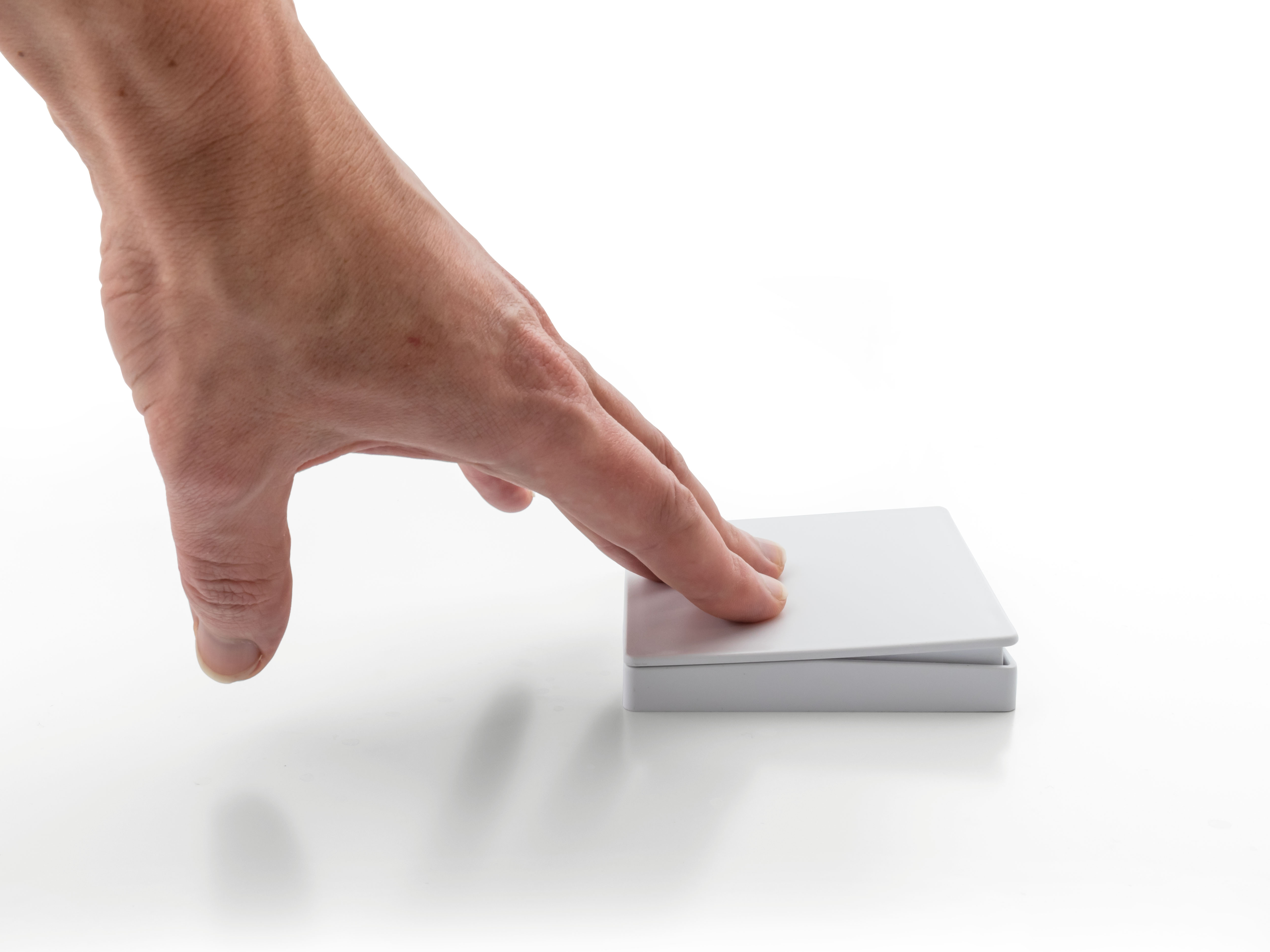 Hand, die sich einer weißen quadratischen Box auf weißem Hintergrund nähert.