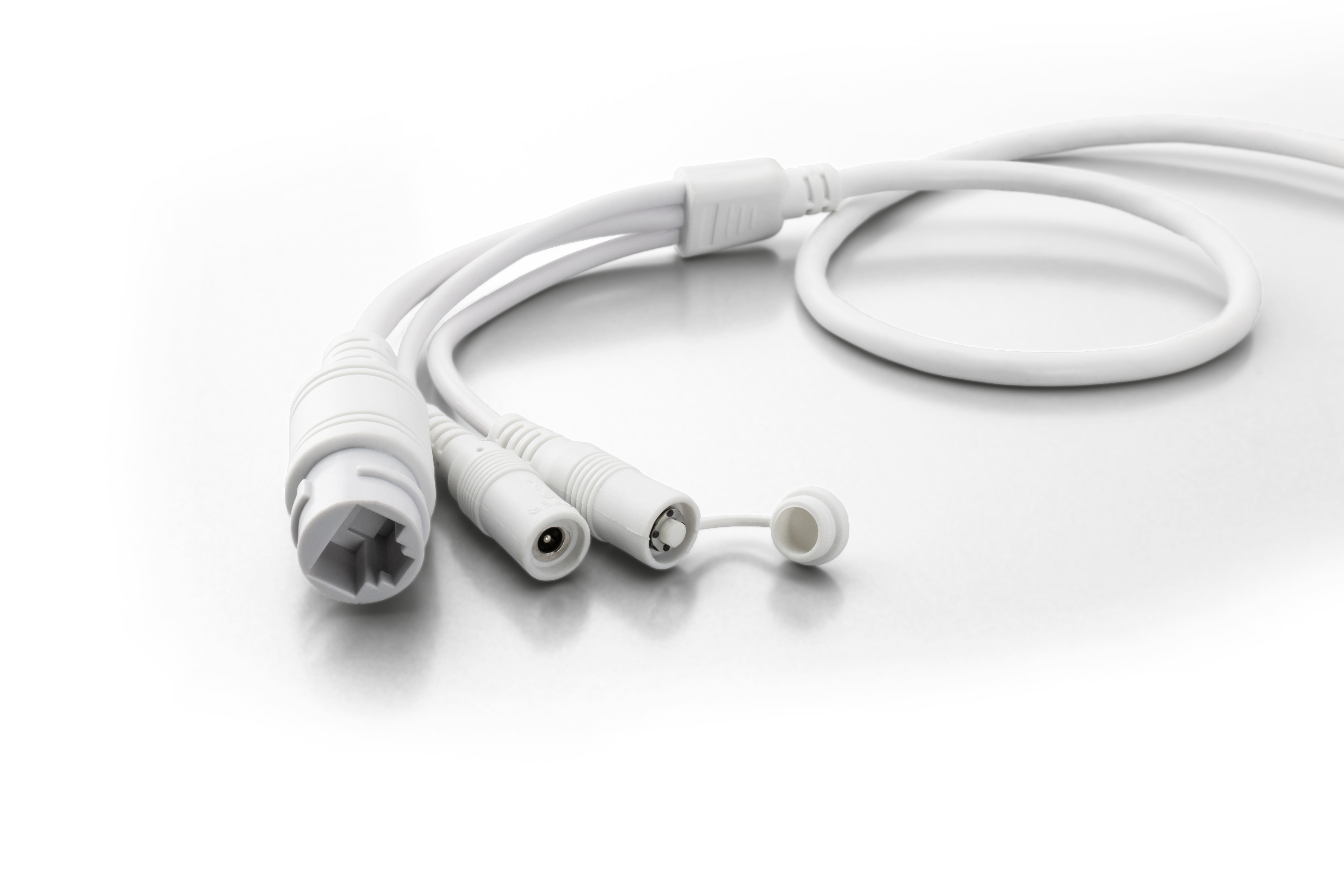 Weißes Kabel mit mehreren Anschlüssen auf weißer Oberfläche. Zu den Anschlüssen gehören ein Ethernet-Port und andere.