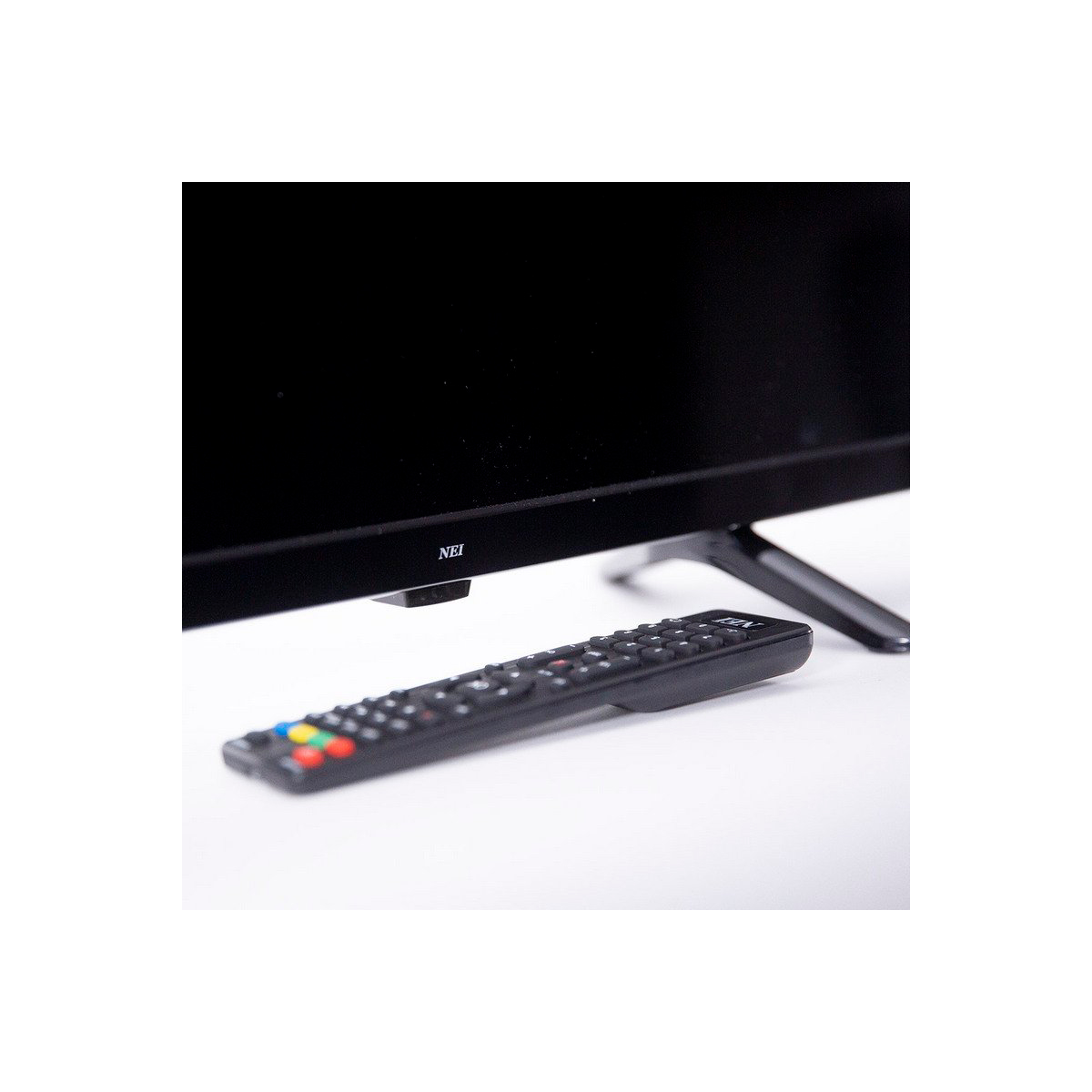 Una TV nera con un telecomando nero davanti, su una superficie bianca.