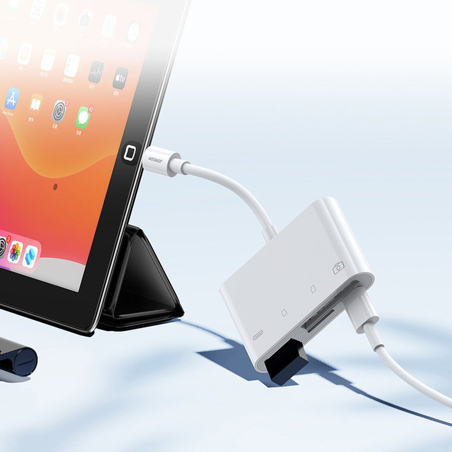 Weißer Kartenleser, der mit einem Tablet verbunden ist. Ein Kabel und eine SD-Karte sind ebenfalls sichtbar.