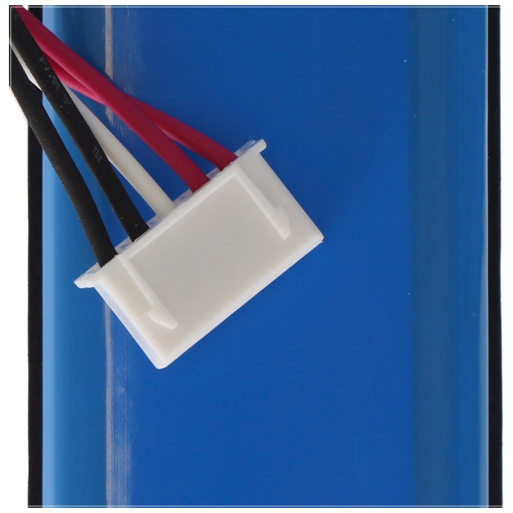 Ein weißer Stecker mit roten, schwarzen und weißen Drähten vor blauem Hintergrund, Teil einer elektrischen Komponente.