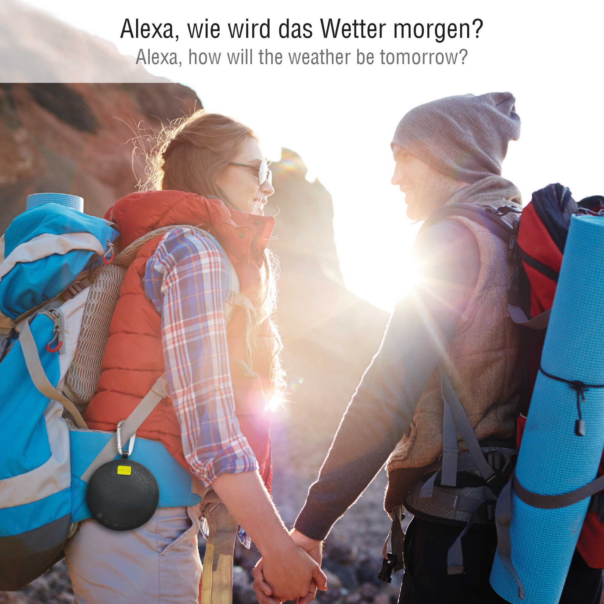 Paar hält sich in der Natur an den Händen, mit einem schwarzen Lautsprecher auf dem Rucksack. Wettertext.