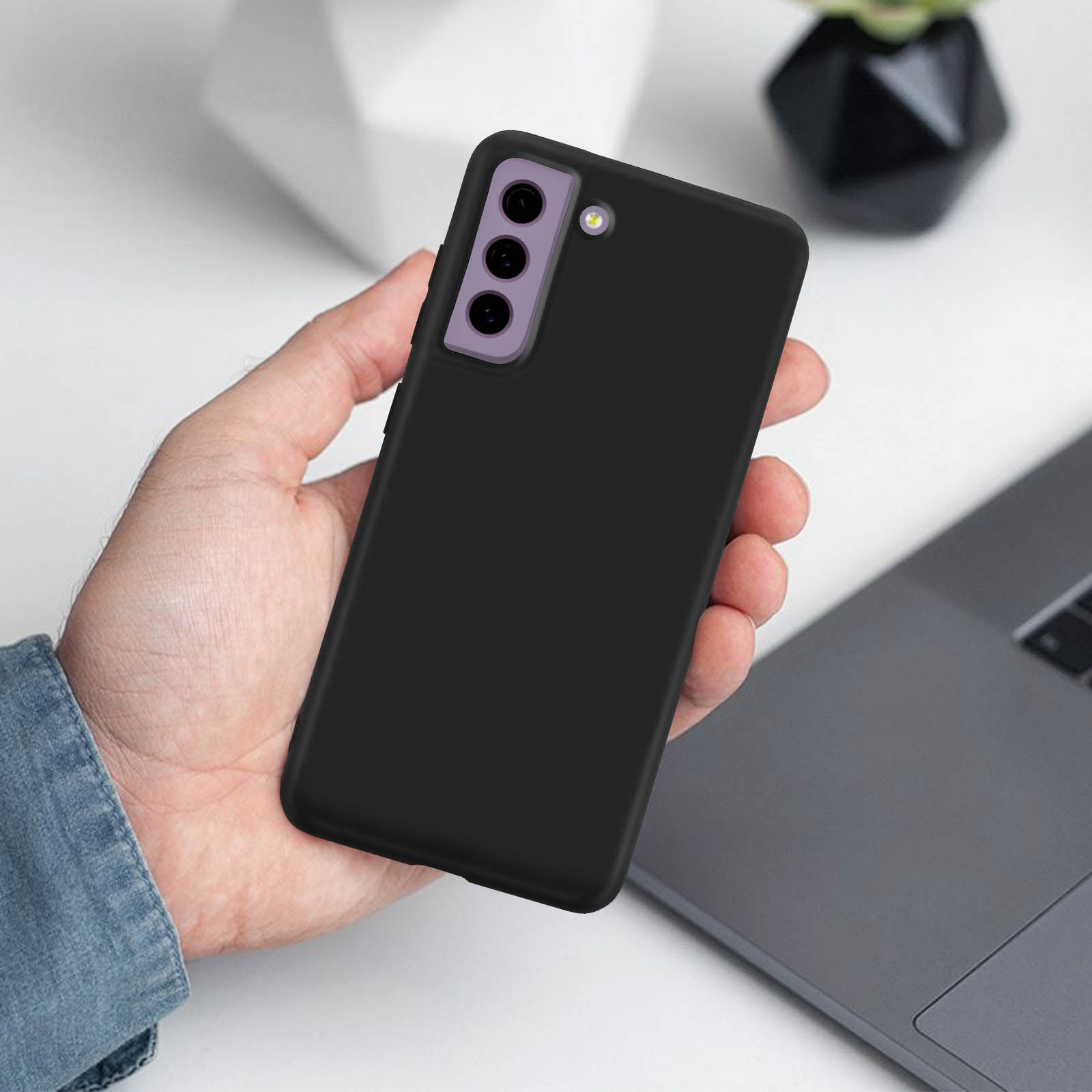Una mano che tiene un telefono nero con tre fotocamere viola.
