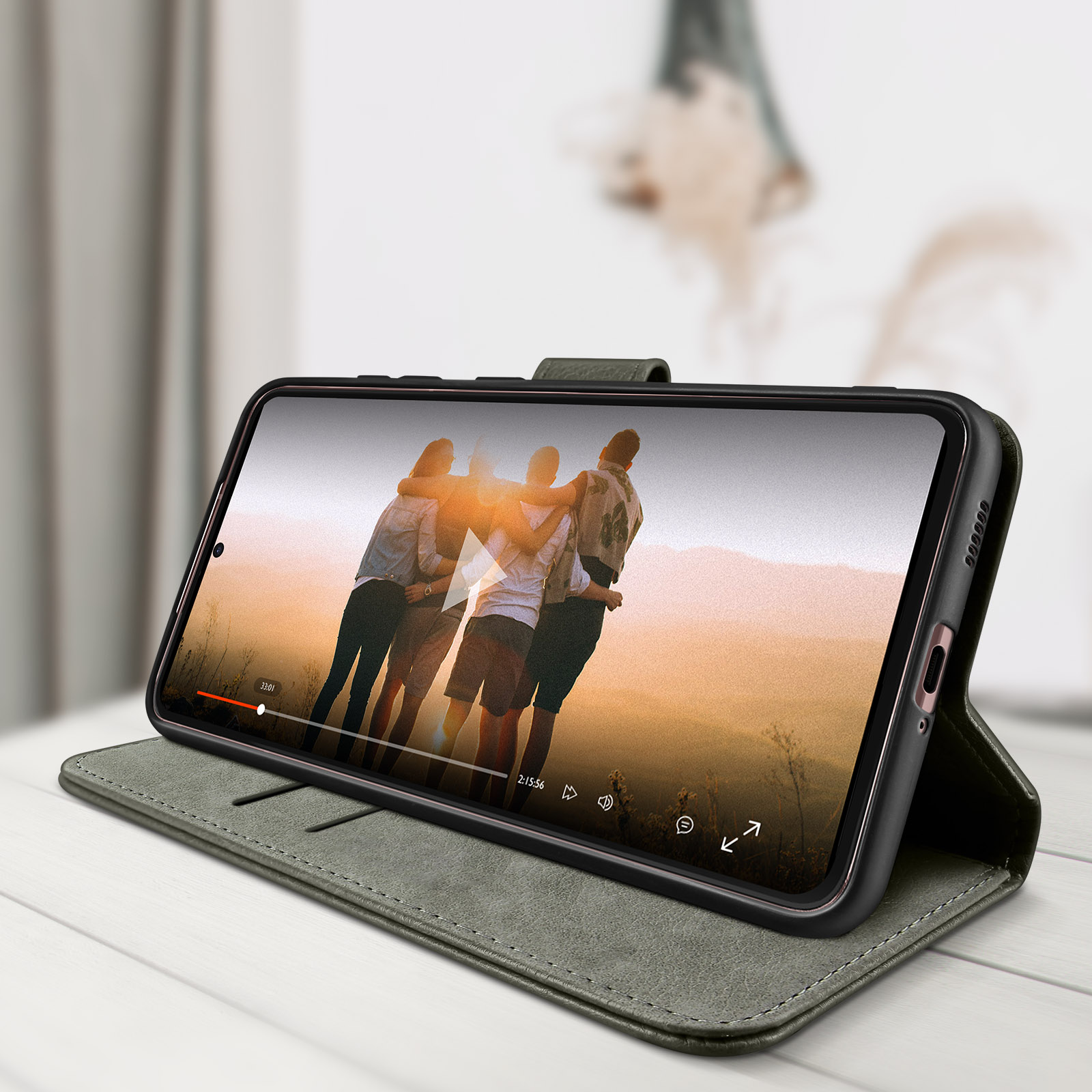 Téléphone affichant une vidéo avec 4 personnes. Le téléphone est dans un étui en cuir vert.