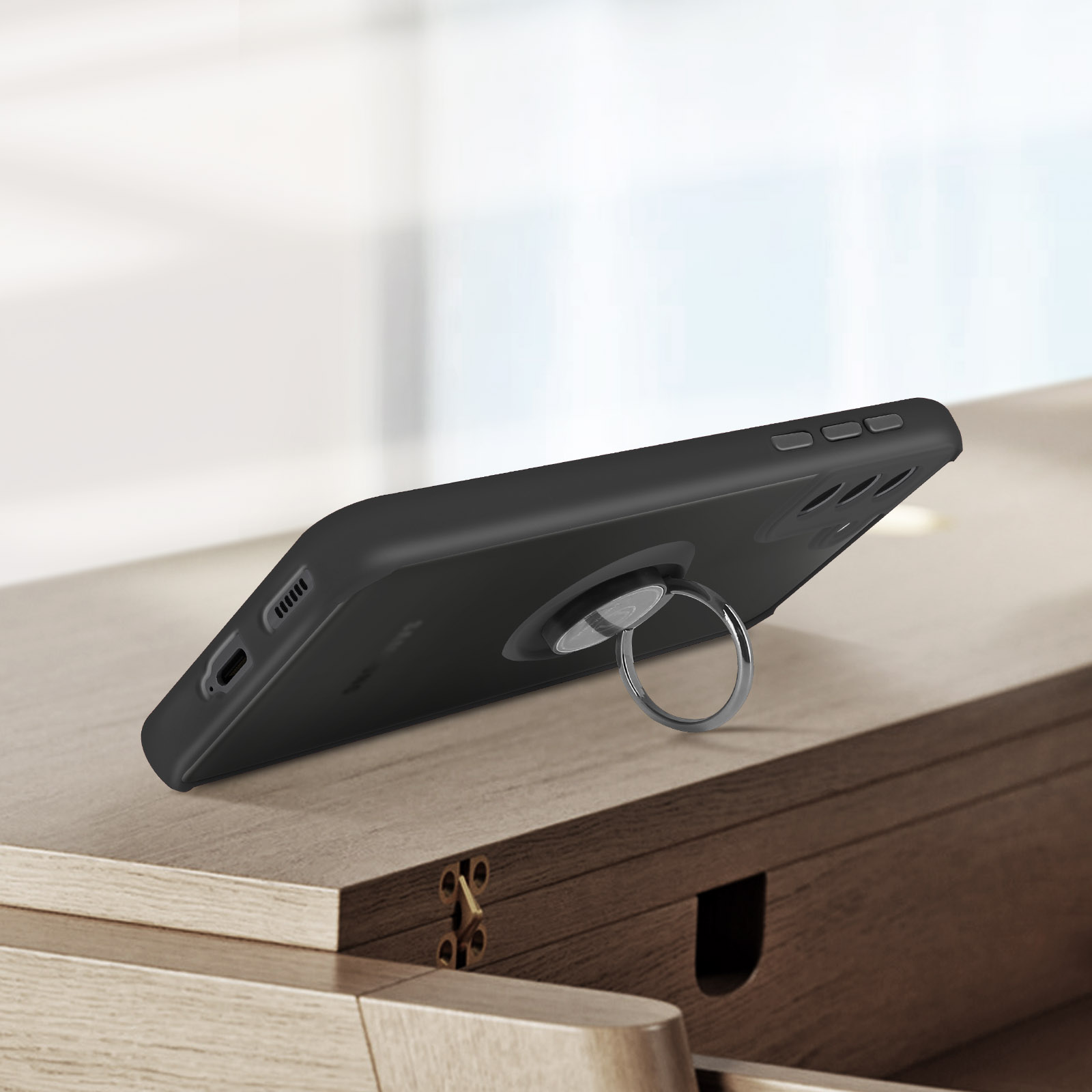 Telefono nero con supporto ad anello su superficie in legno.