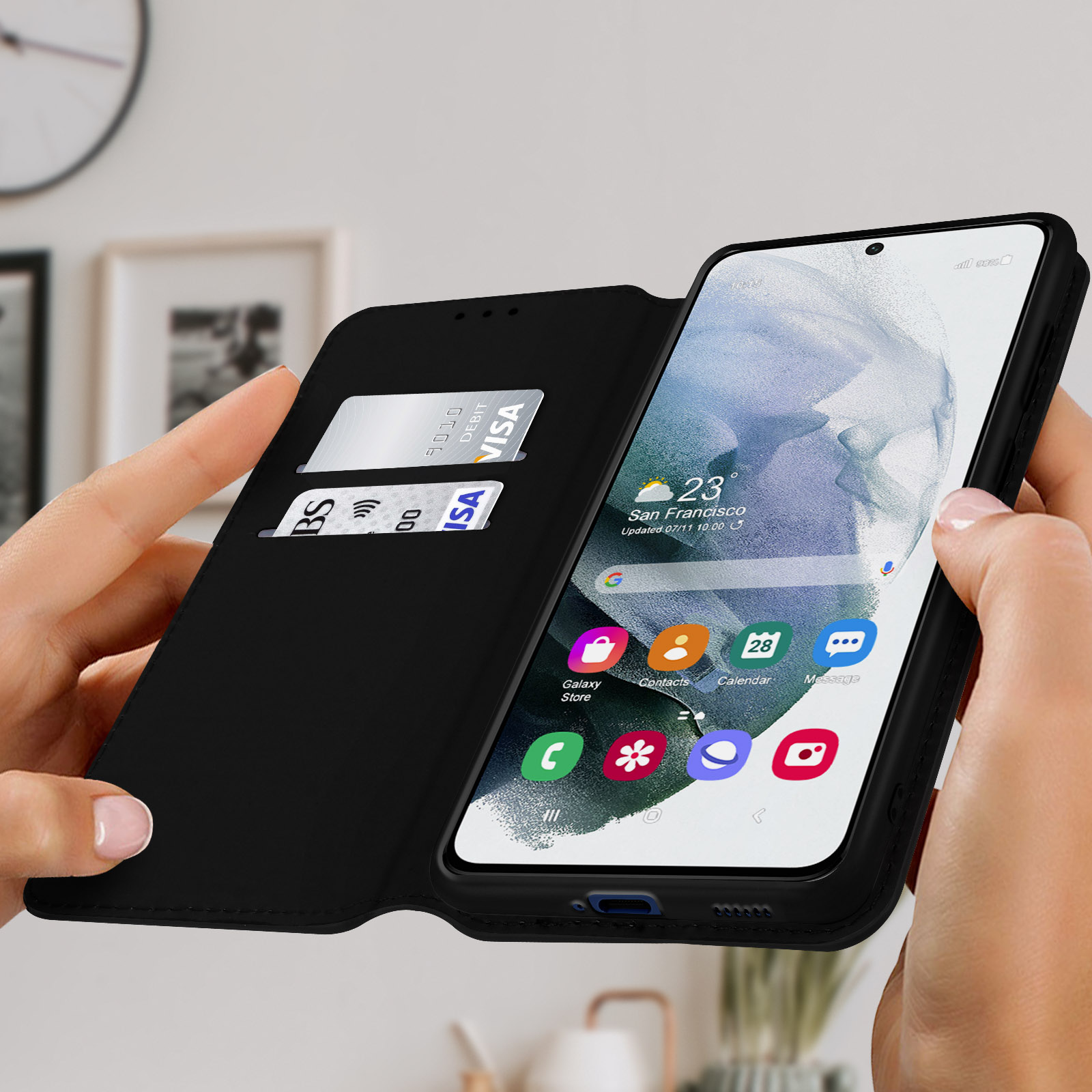 De handen van een vrouw houden een zwarte telefoonhoes open met een telefoon erin. Er zitten creditcards in de hoes.