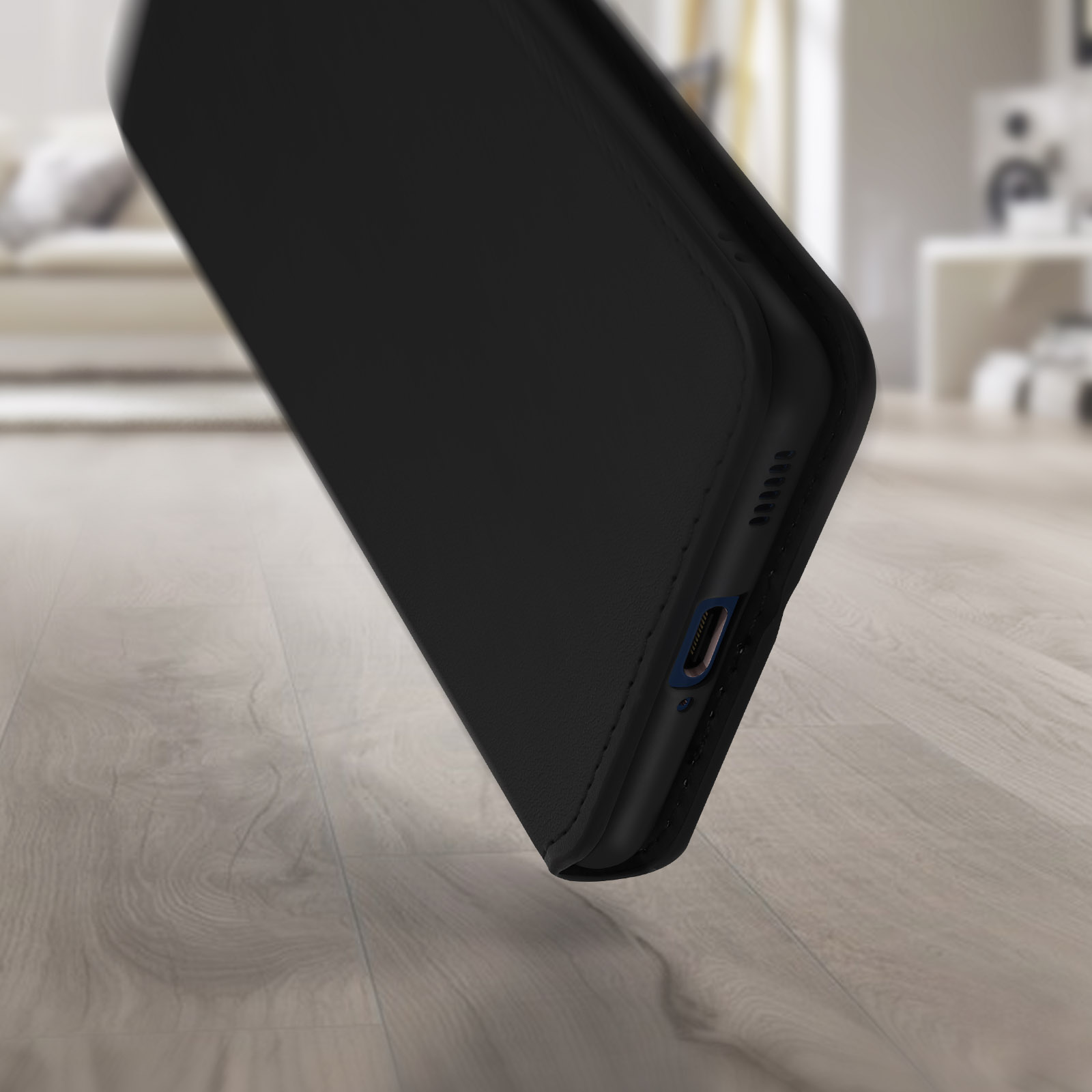 Un étui de téléphone noir sur un plancher en bois. L'étui est légèrement incliné vers la caméra.