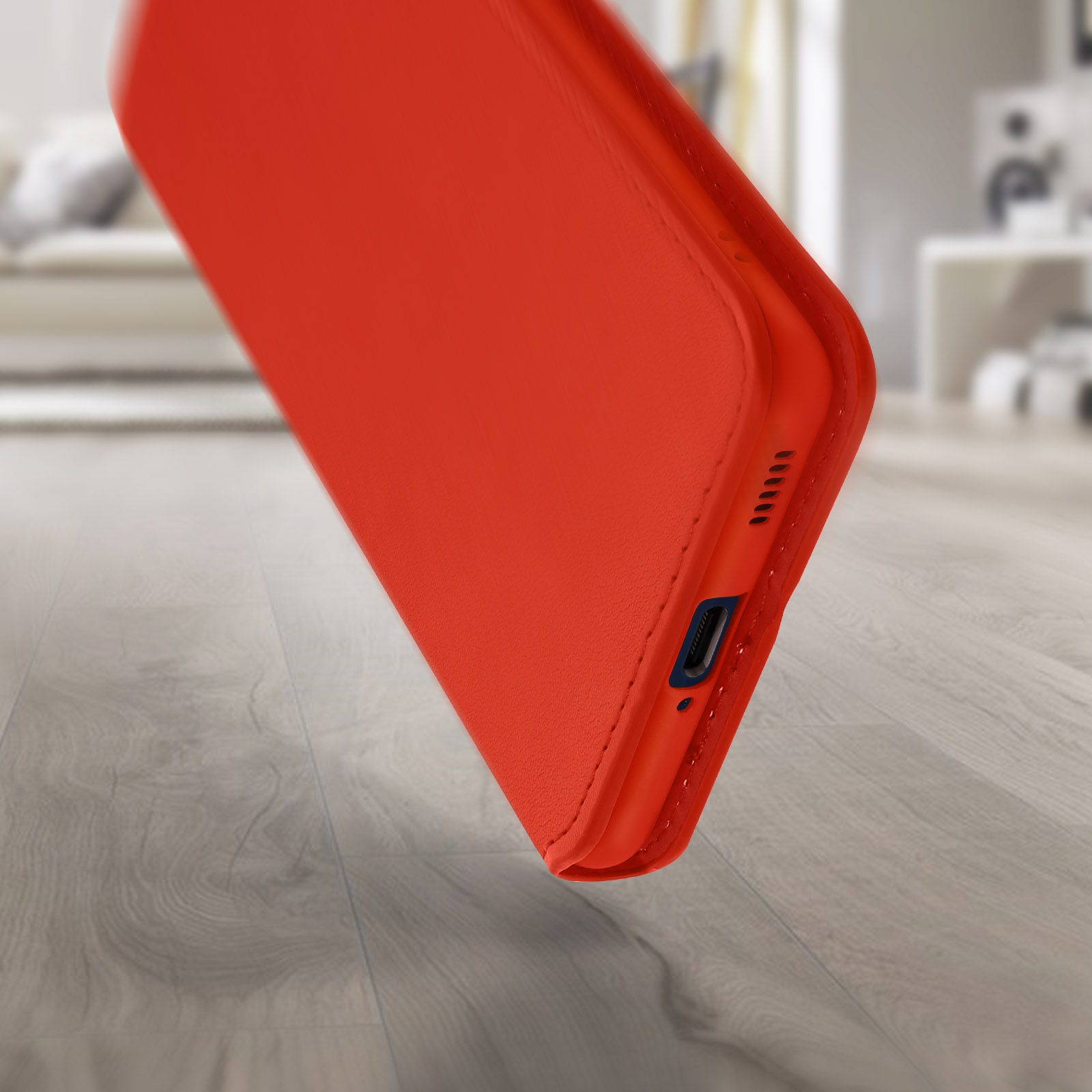 Un primo piano di una custodia per telefono arancione angolata su un pavimento in legno, che mostra una porta di ricarica.