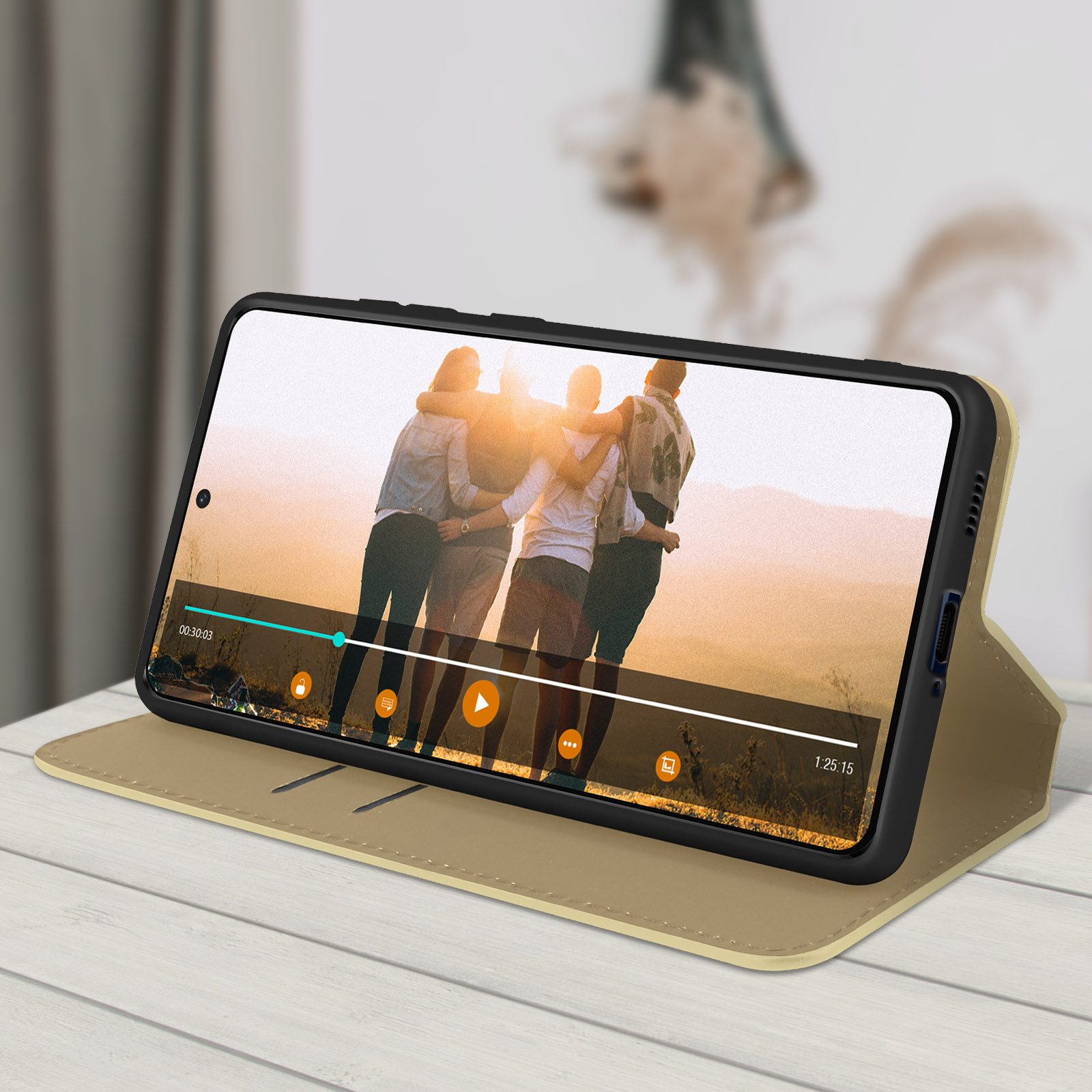 Un telefono che mostra un video in una custodia beige, su una superficie di legno bianca.