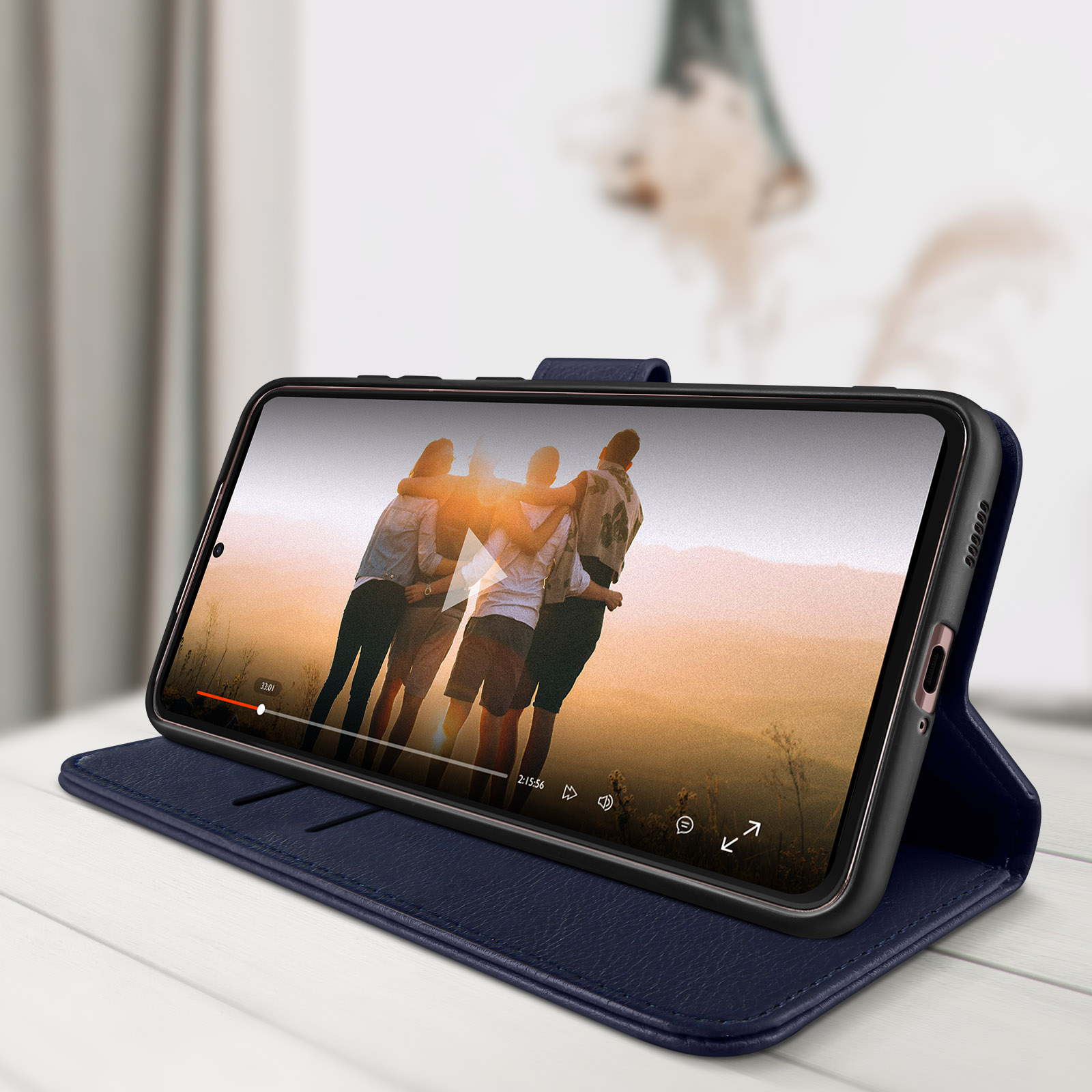 Téléphone lisant une vidéo dans un étui bleu sur une table blanche.